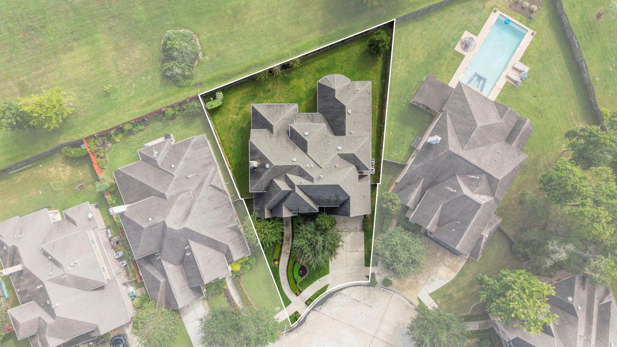 Aerial view of a home and its outlined lot, with a front driveway and lawn.