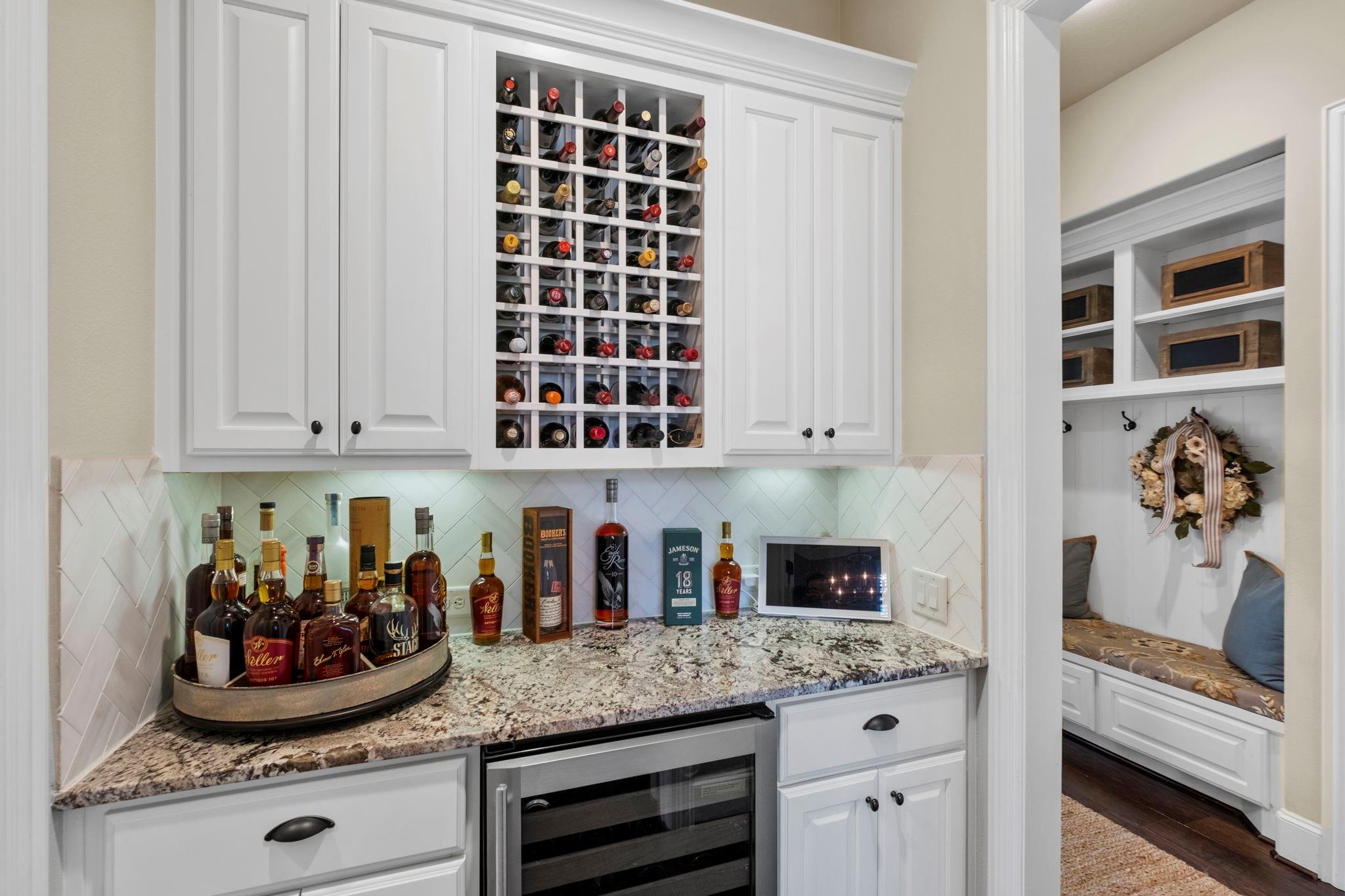 Home bar with built-in wine rack, granite counter, and an adjoining cushioned bench nook.