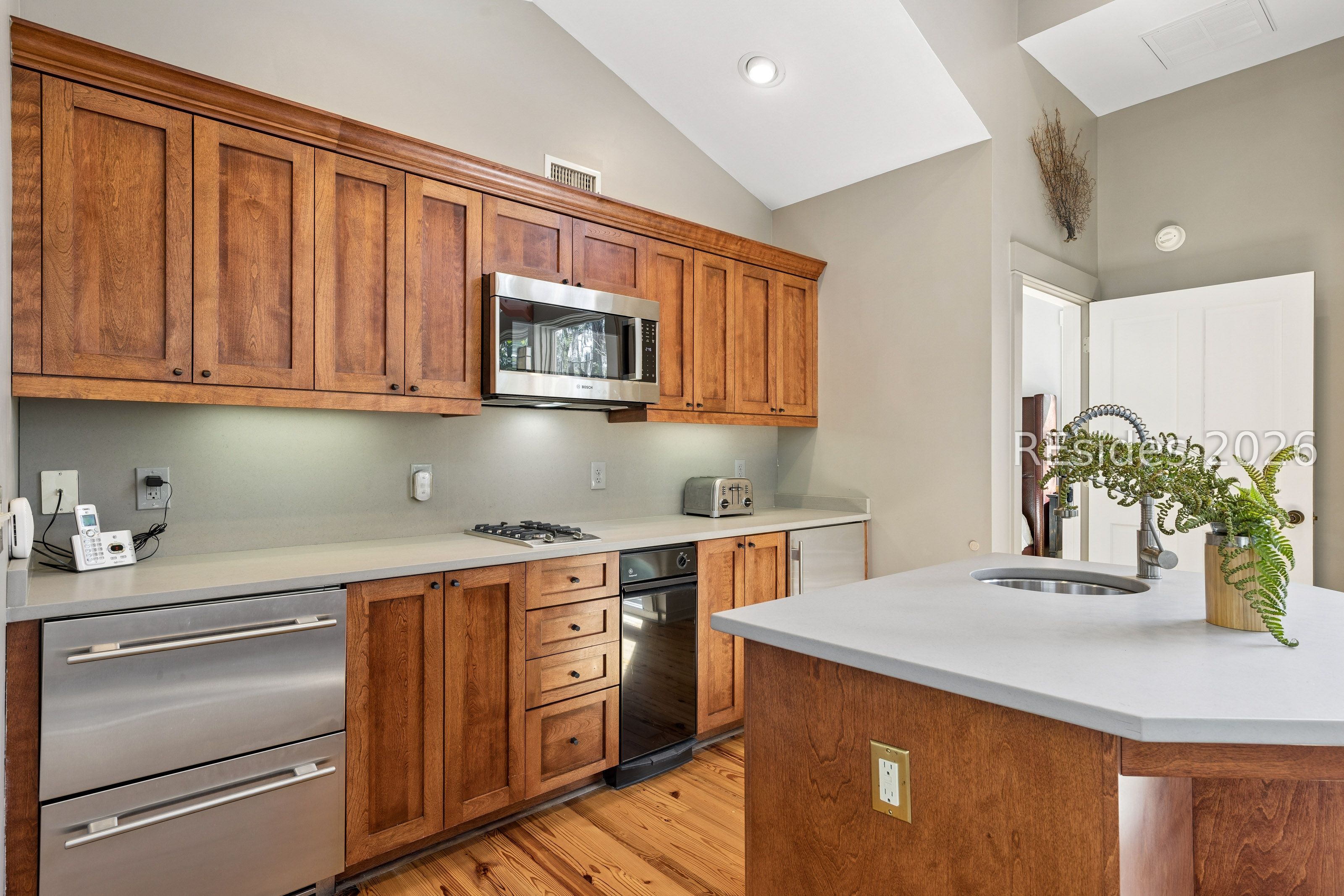 Kitchen with warm wood cabinets, stainless steel appliances, and a large island with sink.