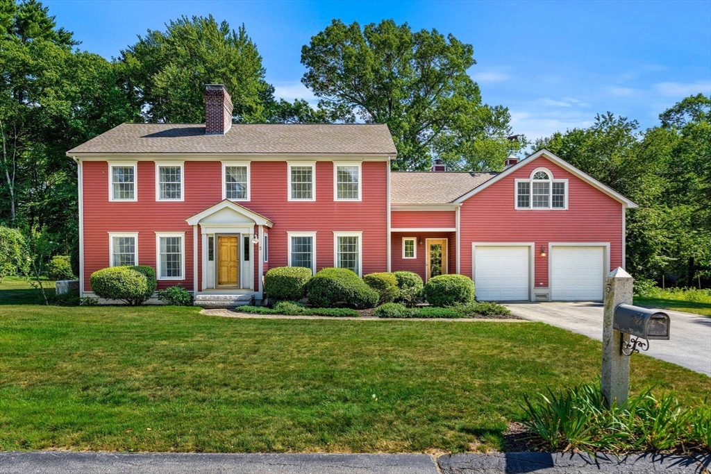 Red two-story house with white trim, attached double garage, and a broad front lawn.
