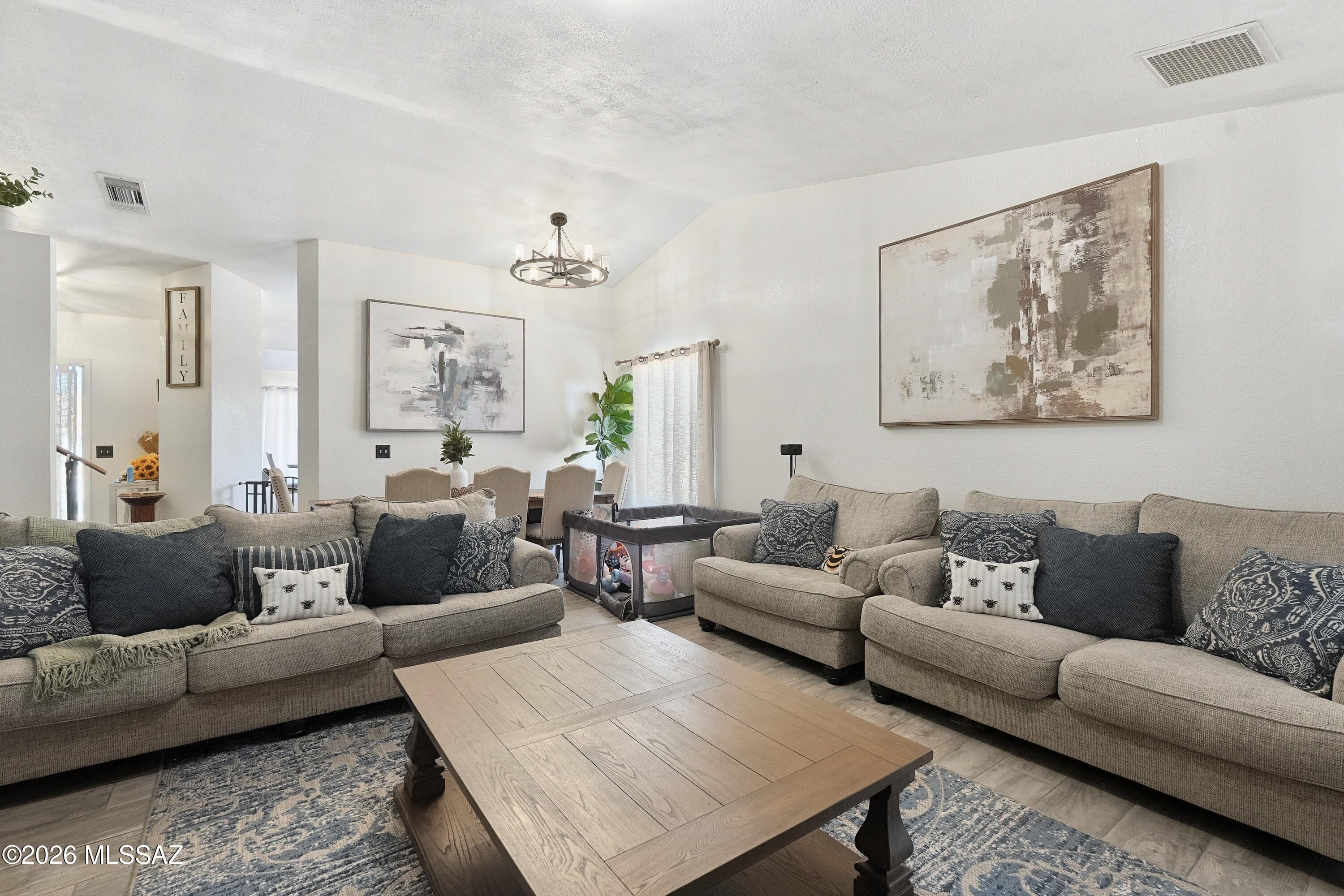 Furnished living room with beige sofas, a large wooden coffee table, and a dining area beyond.