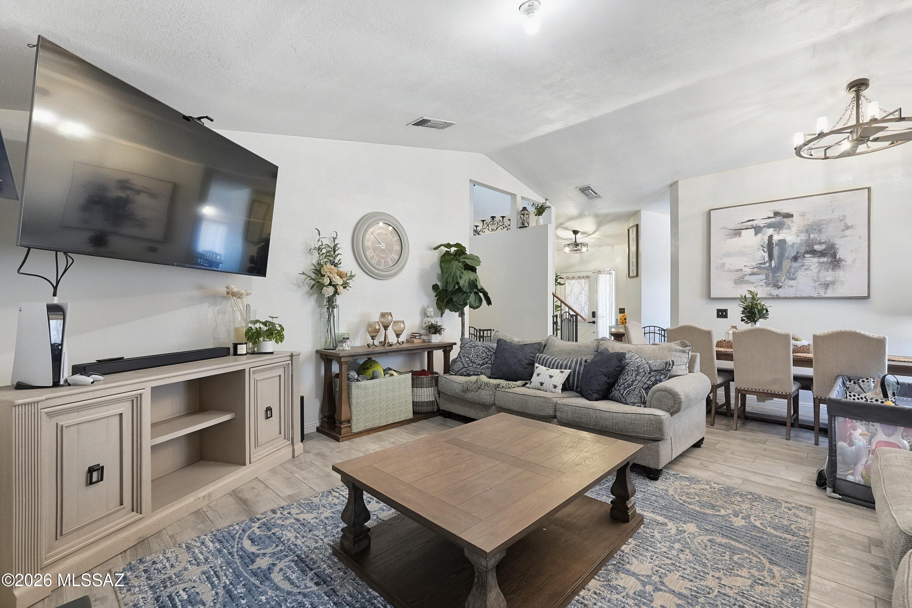 Furnished living room with a gray sectional, large wall-mounted TV, and wood coffee table.