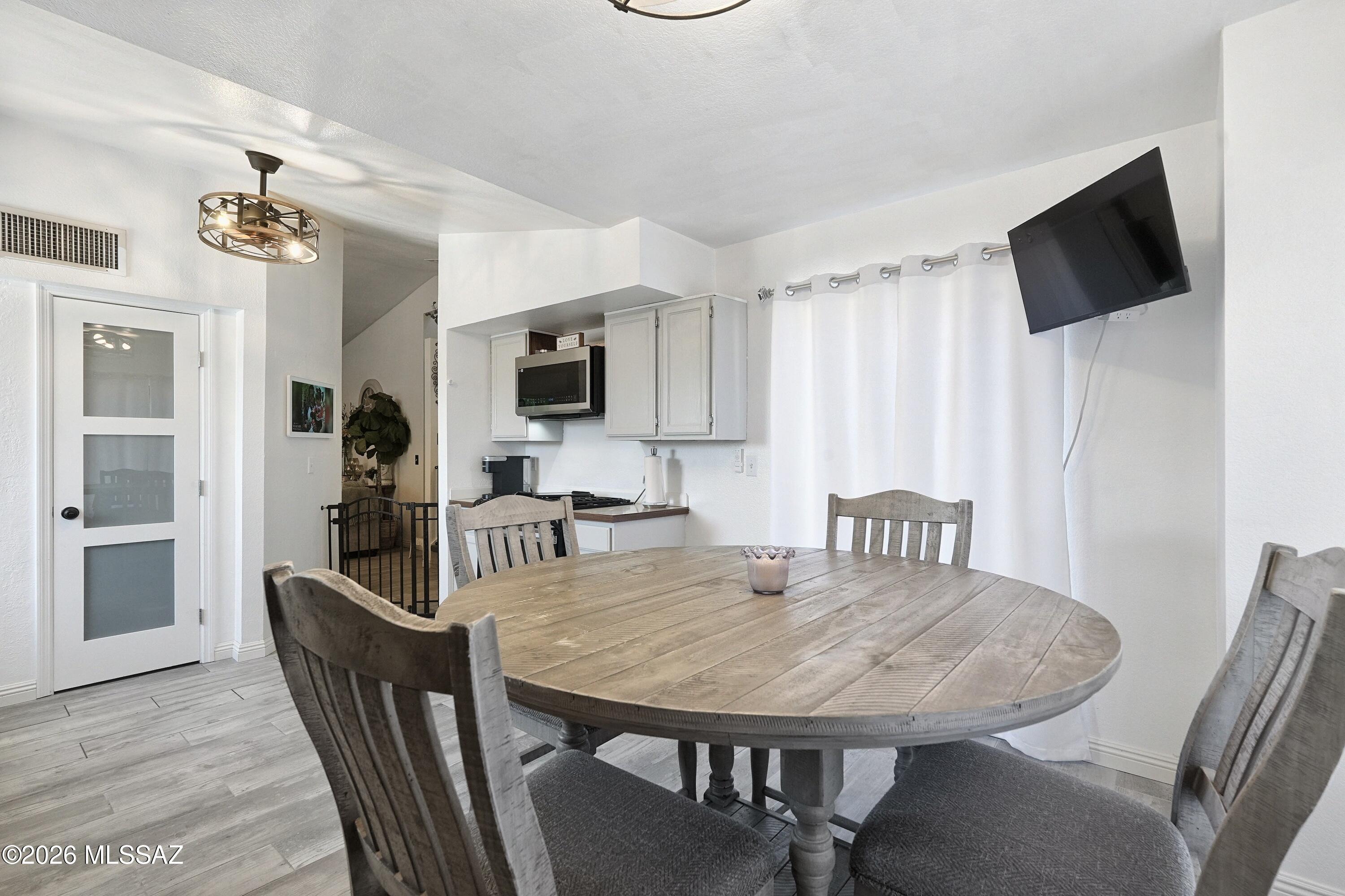 Dining area with a large oval wood table beside a compact white-cabinet kitchen.