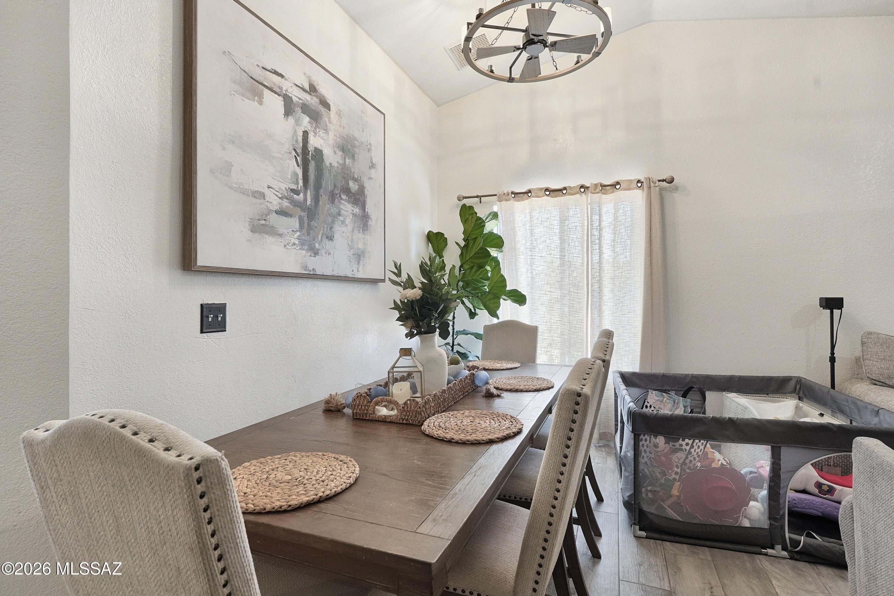 Dining room with a dark wood table, upholstered chairs, and a playpen beside the window.