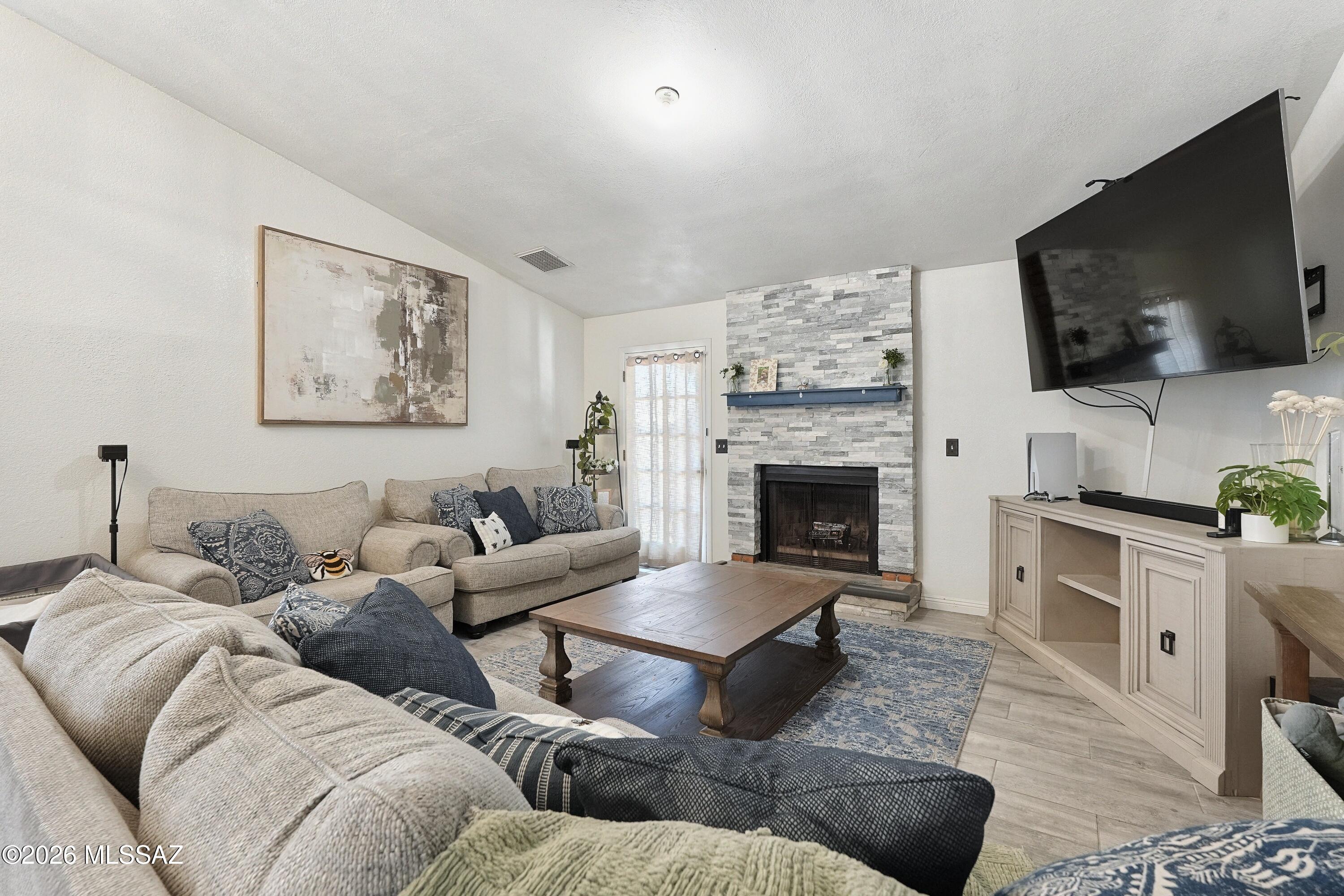 Living room with a stacked-stone fireplace, sectional sofas, and a large wall-mounted television.