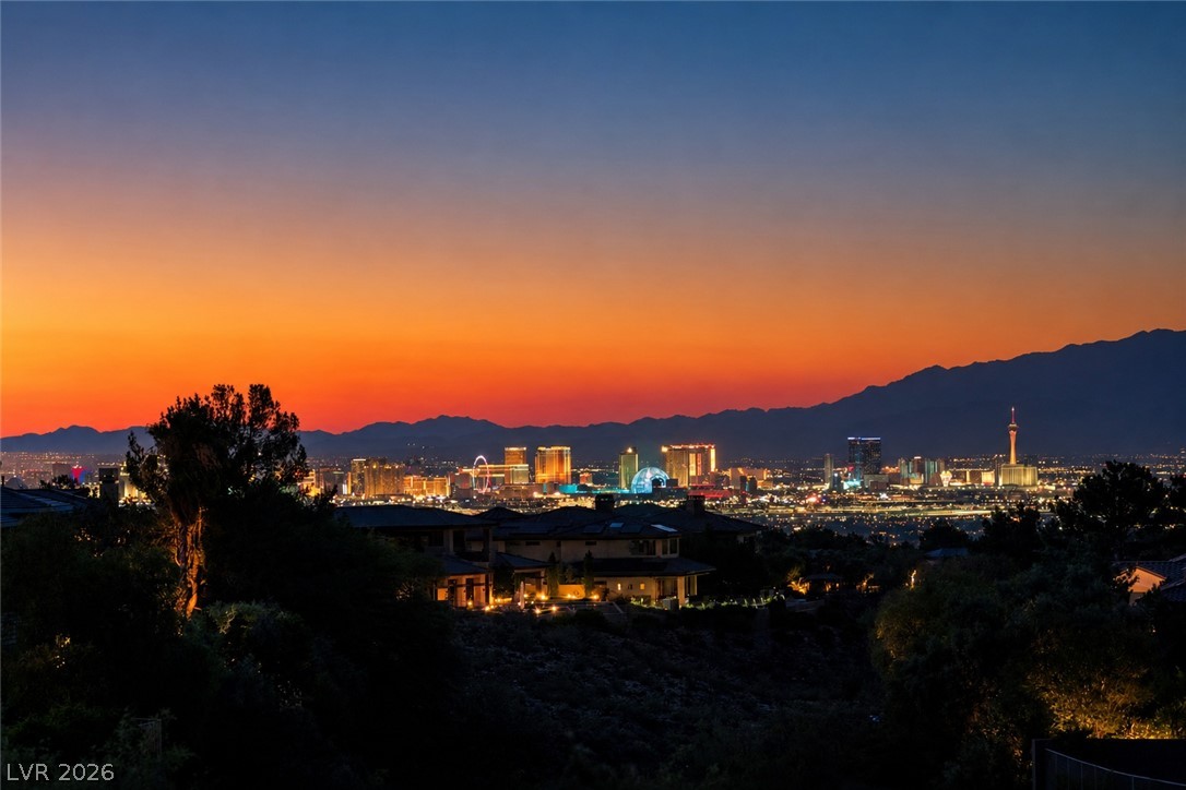 Las Vegas skyline at dusk, framed by mountains and homes in the foreground.