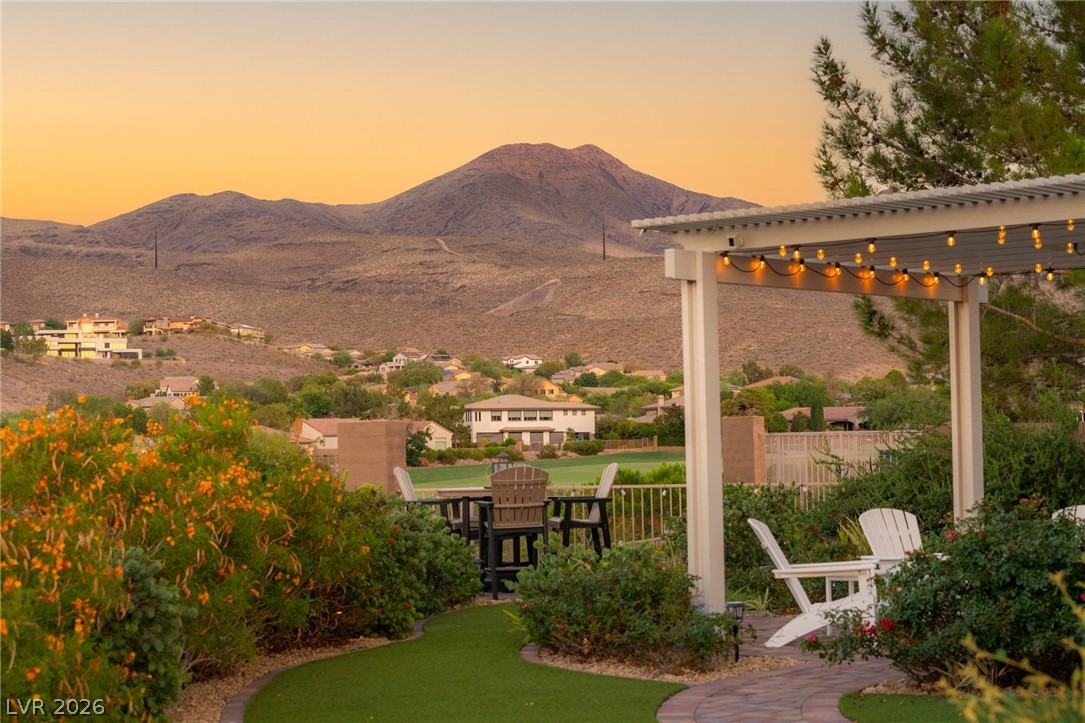 Backyard patio with pergola and seating overlooking desert mountains at sunset.