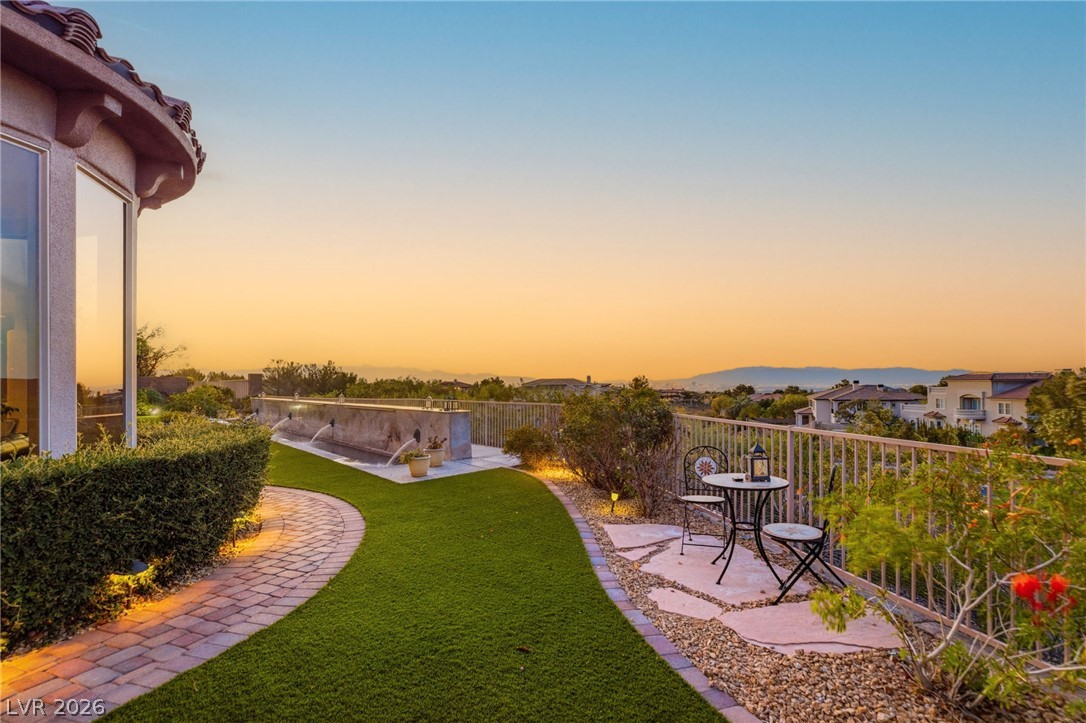 Backyard patio with a curved paver walkway, outdoor seating, and distant mountains at sunset.
