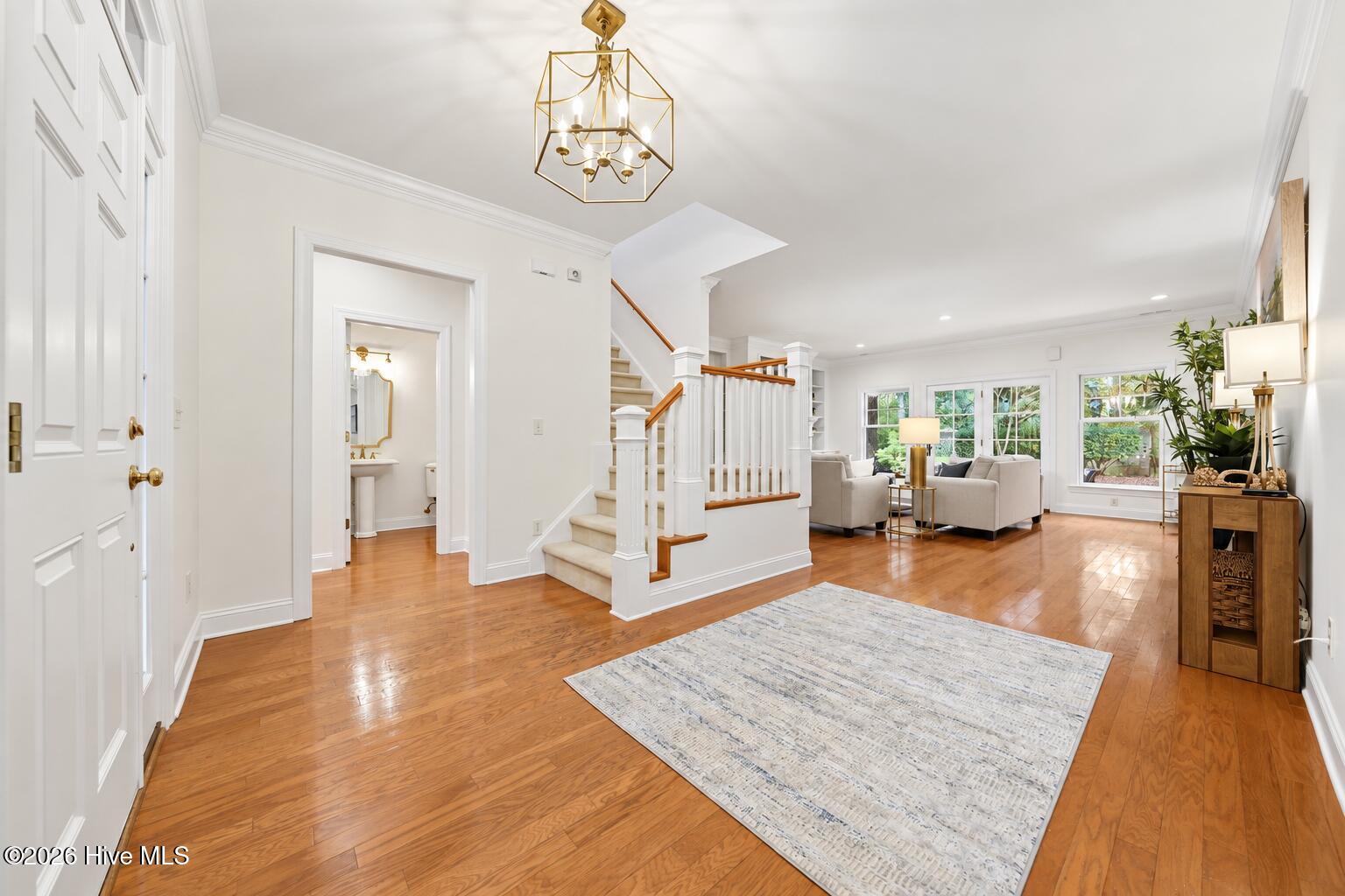 Open living room and entry with hardwood floors, a central staircase, and neutral furnishings.