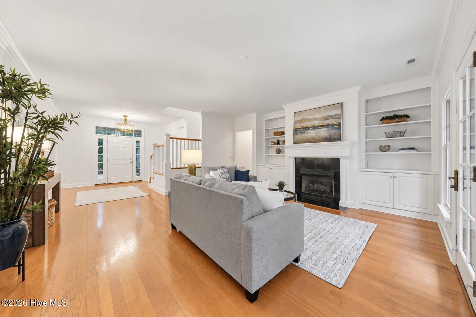 Living room with hardwood floors, a gray sofa, and built-in shelves surrounding a fireplace.