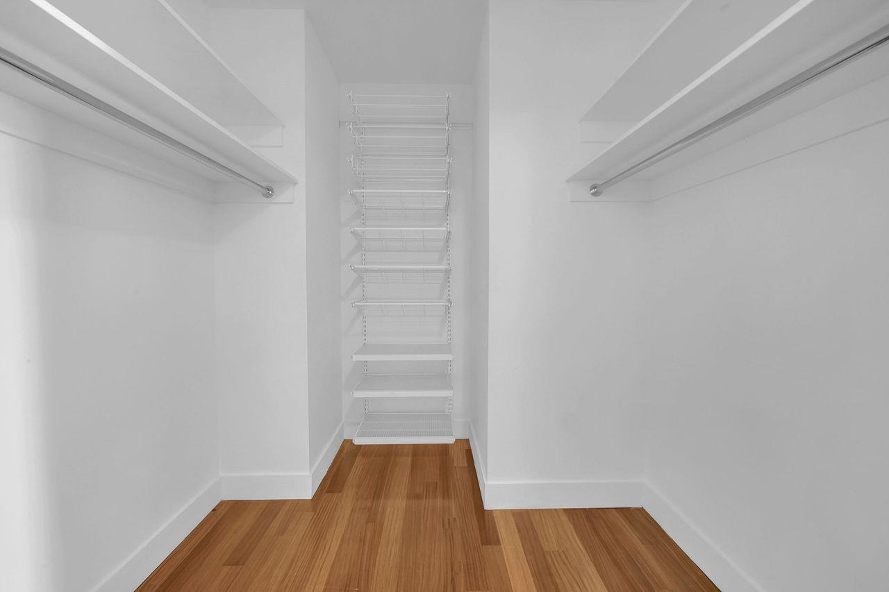 Walk-in closet with built-in wire shelving and hanging rods, and a wood floor.