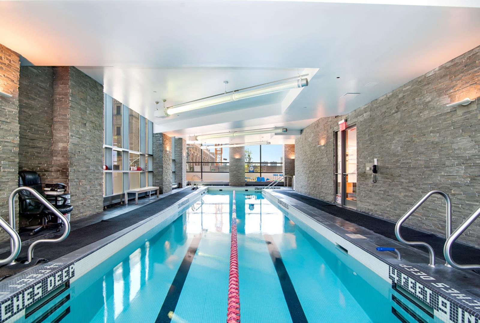 Indoor swimming pool with turquoise water, a red lane divider, and gray stone walls.