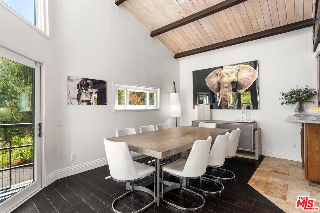 Dining room with a wood table, white chairs, and a vaulted wood-paneled ceiling.