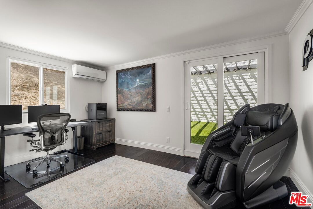 Home office with a large massage chair, dual-monitor desk, and sliding glass doors to a patio.