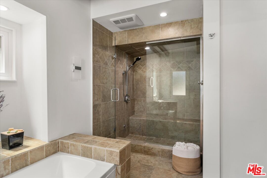 Bathroom with a glass-enclosed tiled shower, built-in bench, and corner bathtub.