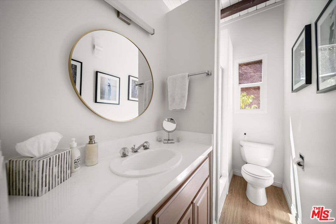 Bathroom with a long white vanity, oval gold-framed mirror, and separate toilet area.