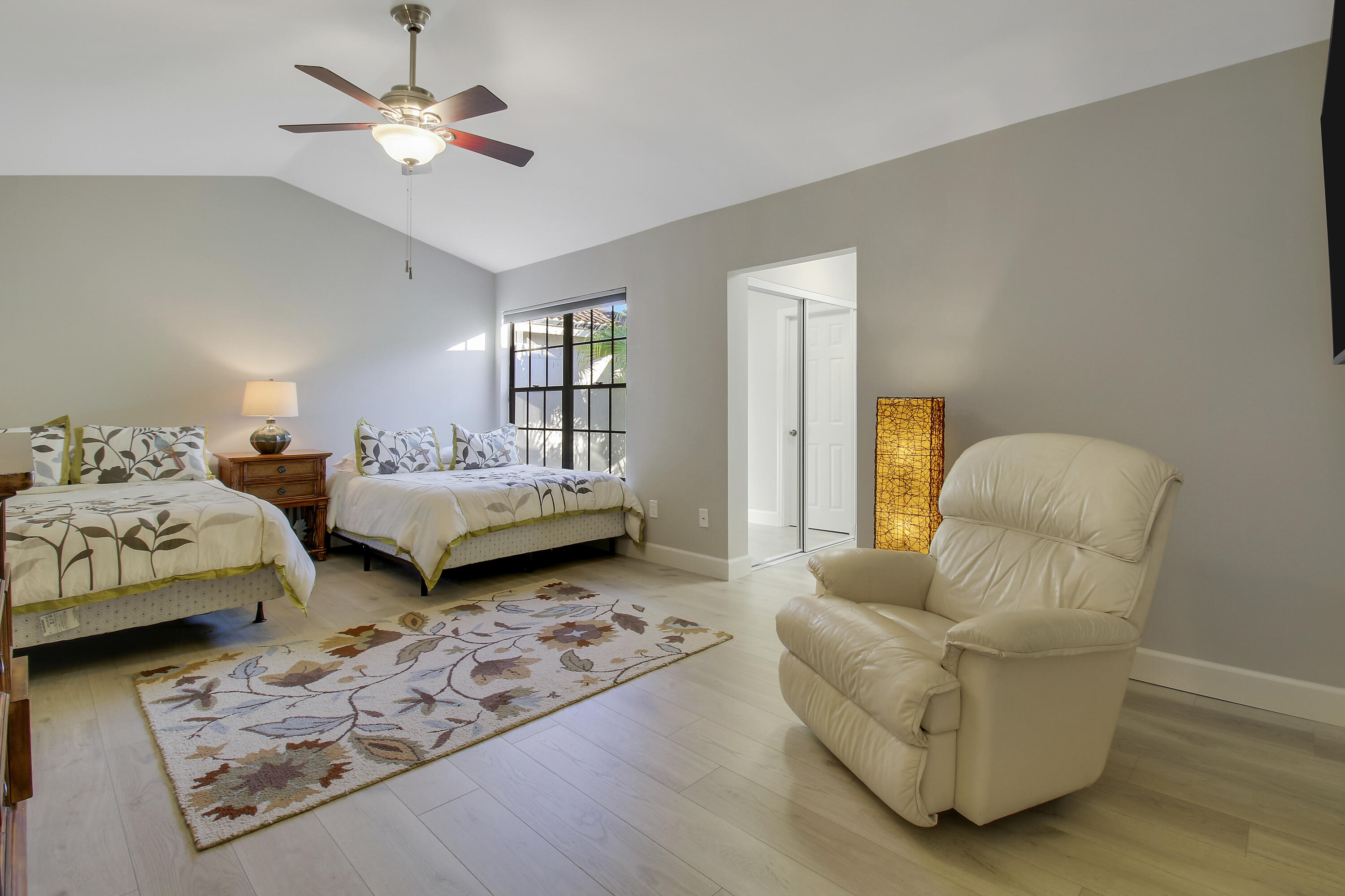 Bedroom with two beds, a floral rug, and a cream leather recliner.