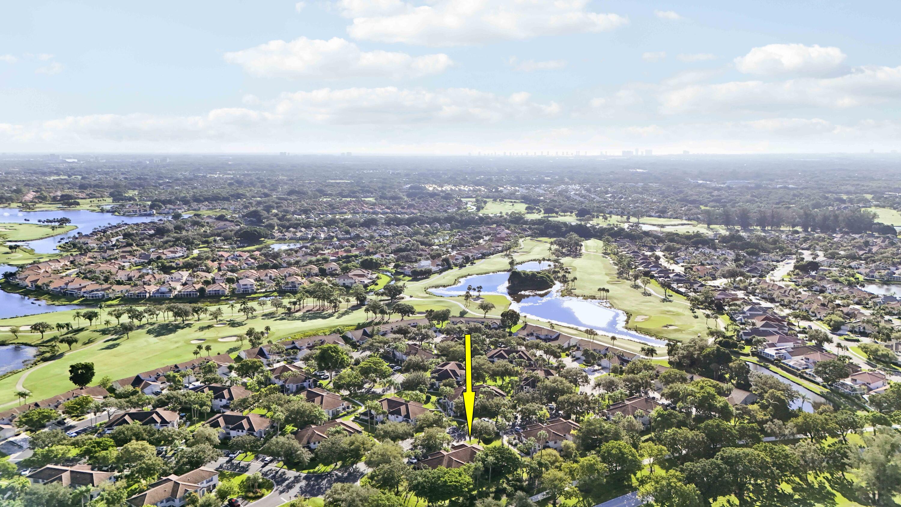 Aerial view of the home marked by a yellow arrow, near golf course fairways and ponds.