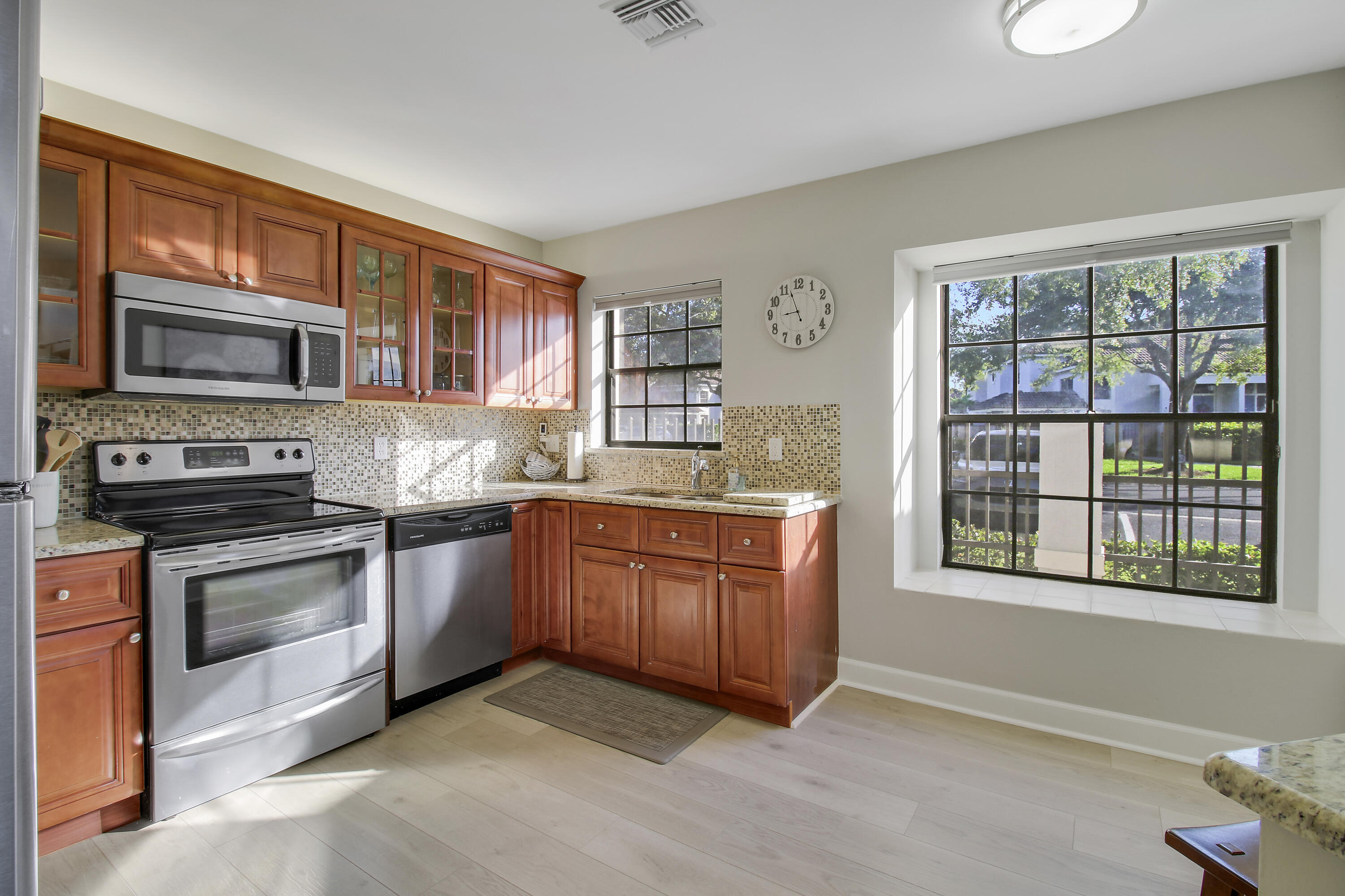 Kitchen with reddish wood cabinets, stainless steel appliances, and large black-grid windows.