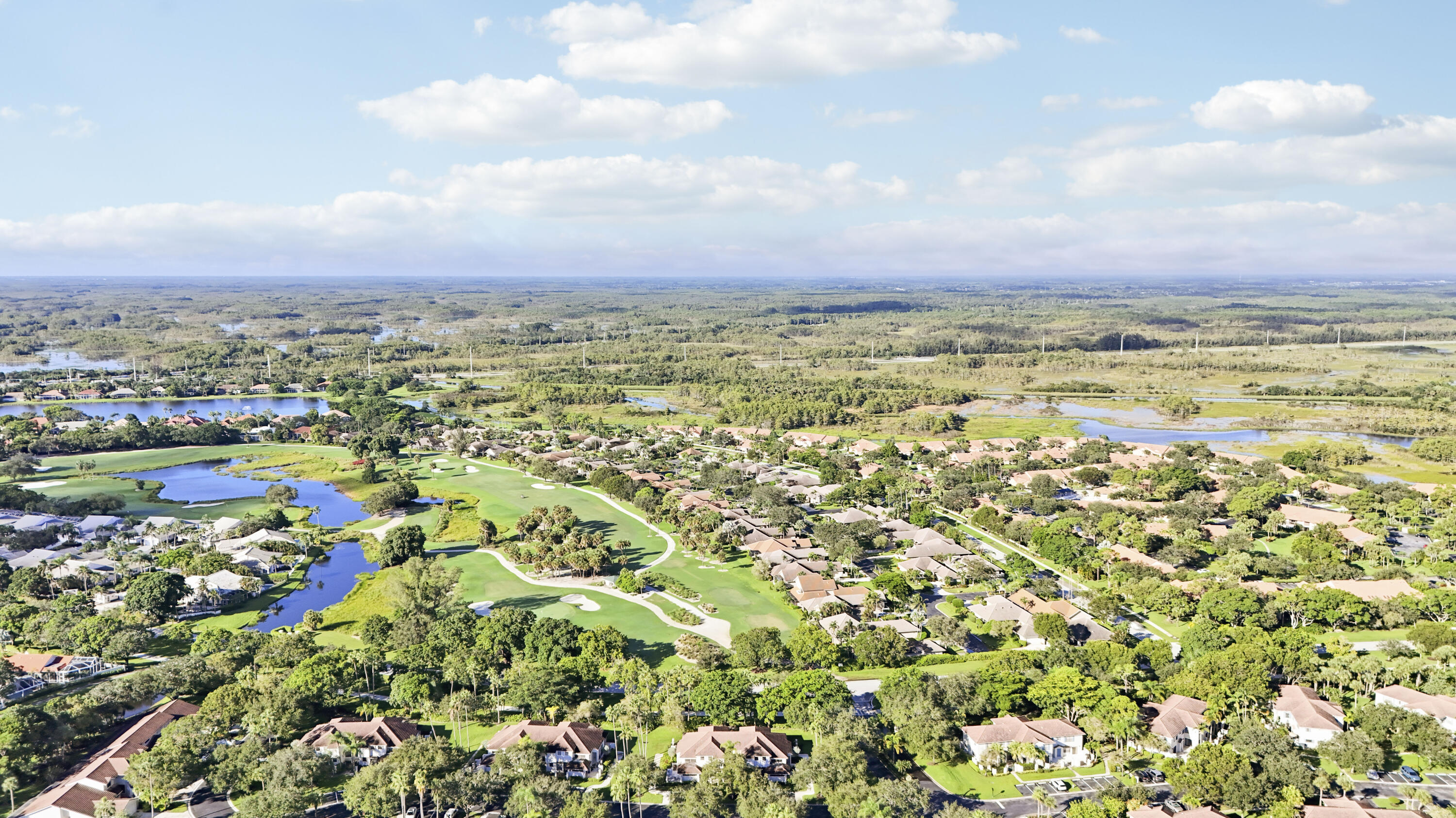 Aerial view of homes along golf course fairways, ponds, and wetlands.