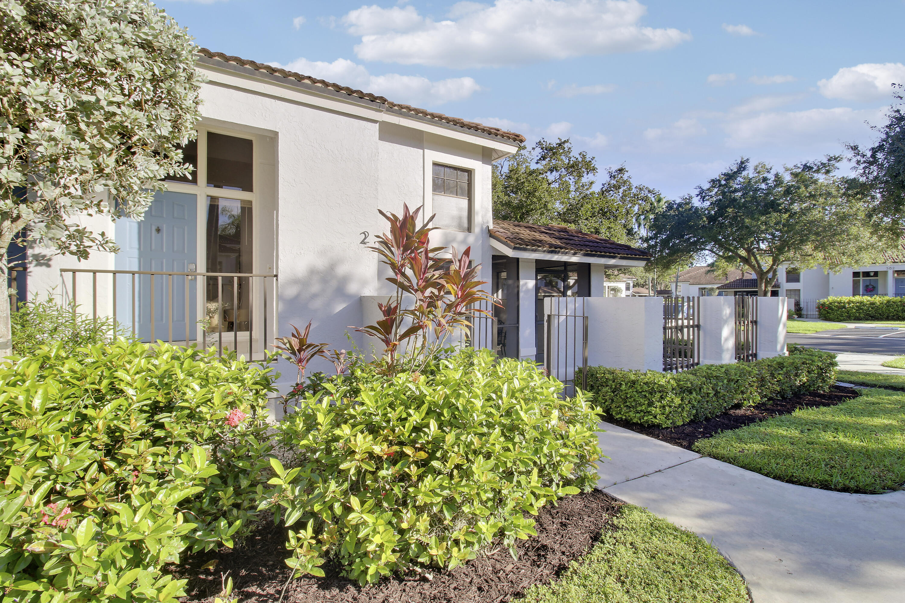 White stucco home marked 2, with a blue front door and landscaped entrance.