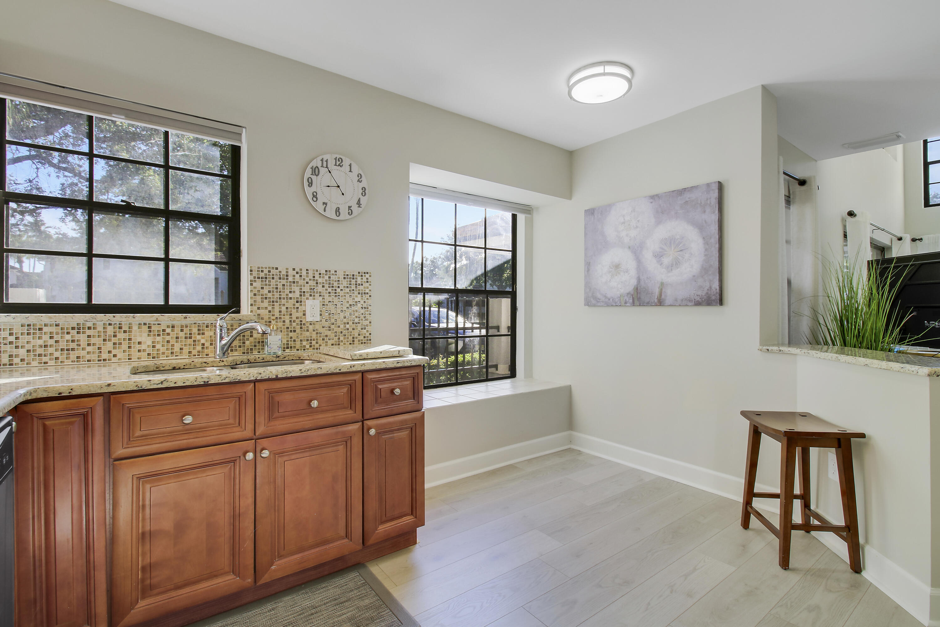 Kitchen with reddish wood cabinets, granite counters, mosaic tile backsplash, and large black-framed windows.