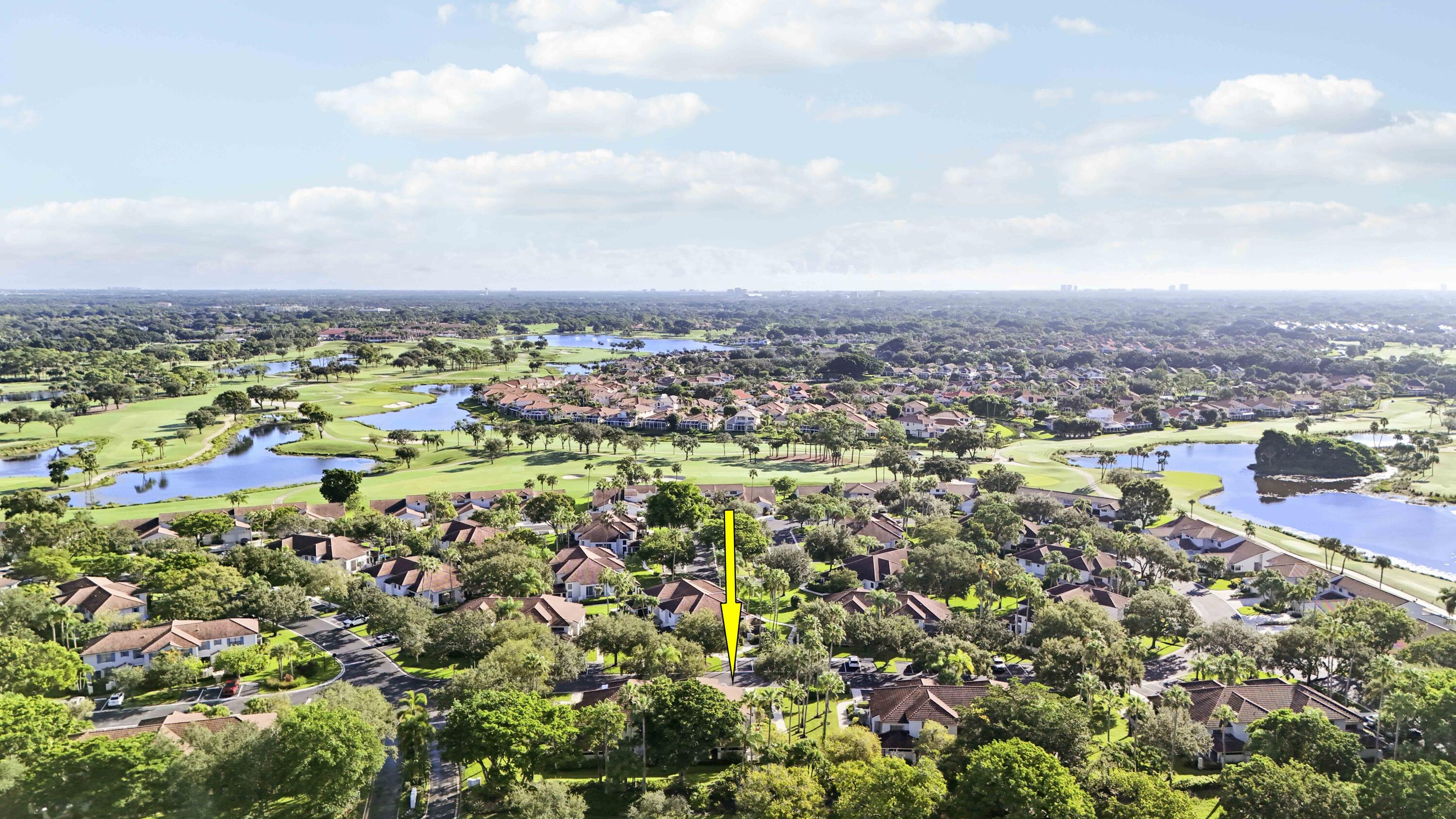 Aerial neighborhood view showing the marked home beside golf course fairways and ponds.
