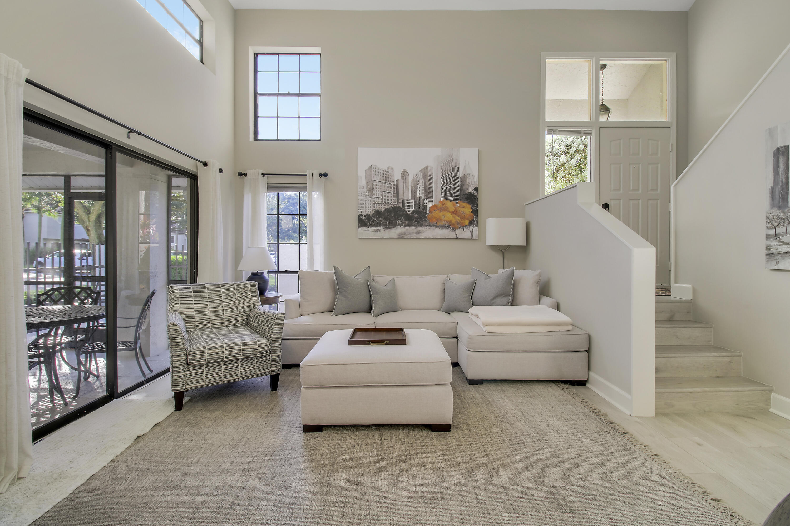 Living room with a beige sectional, striped armchair, and sliding glass doors opening to a patio.