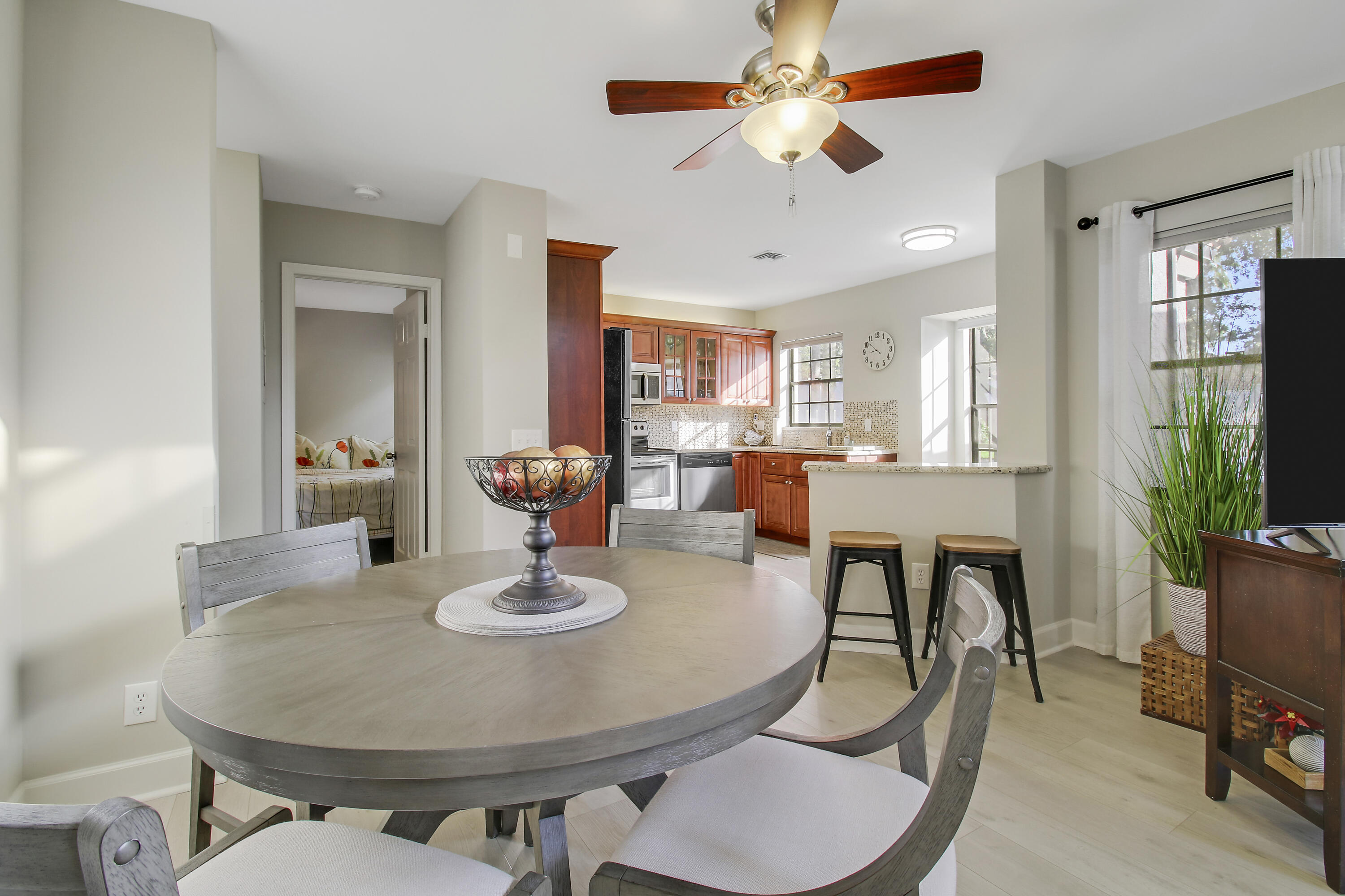 Dining area with a round gray table, opening onto a wood-cabinet kitchen with a breakfast counter.
