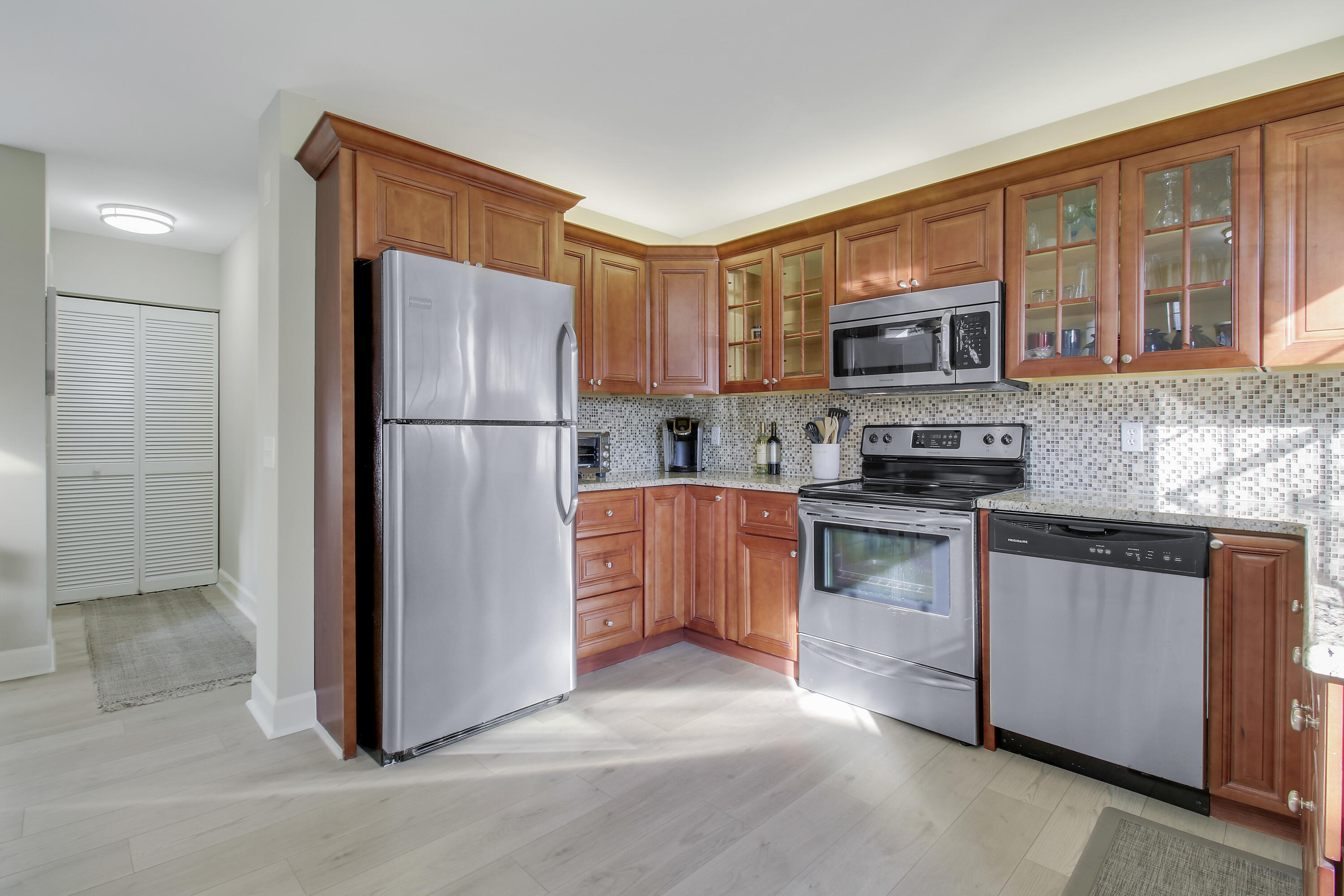 Kitchen with warm wood cabinetry, mosaic tile backsplash, and stainless steel appliances.
