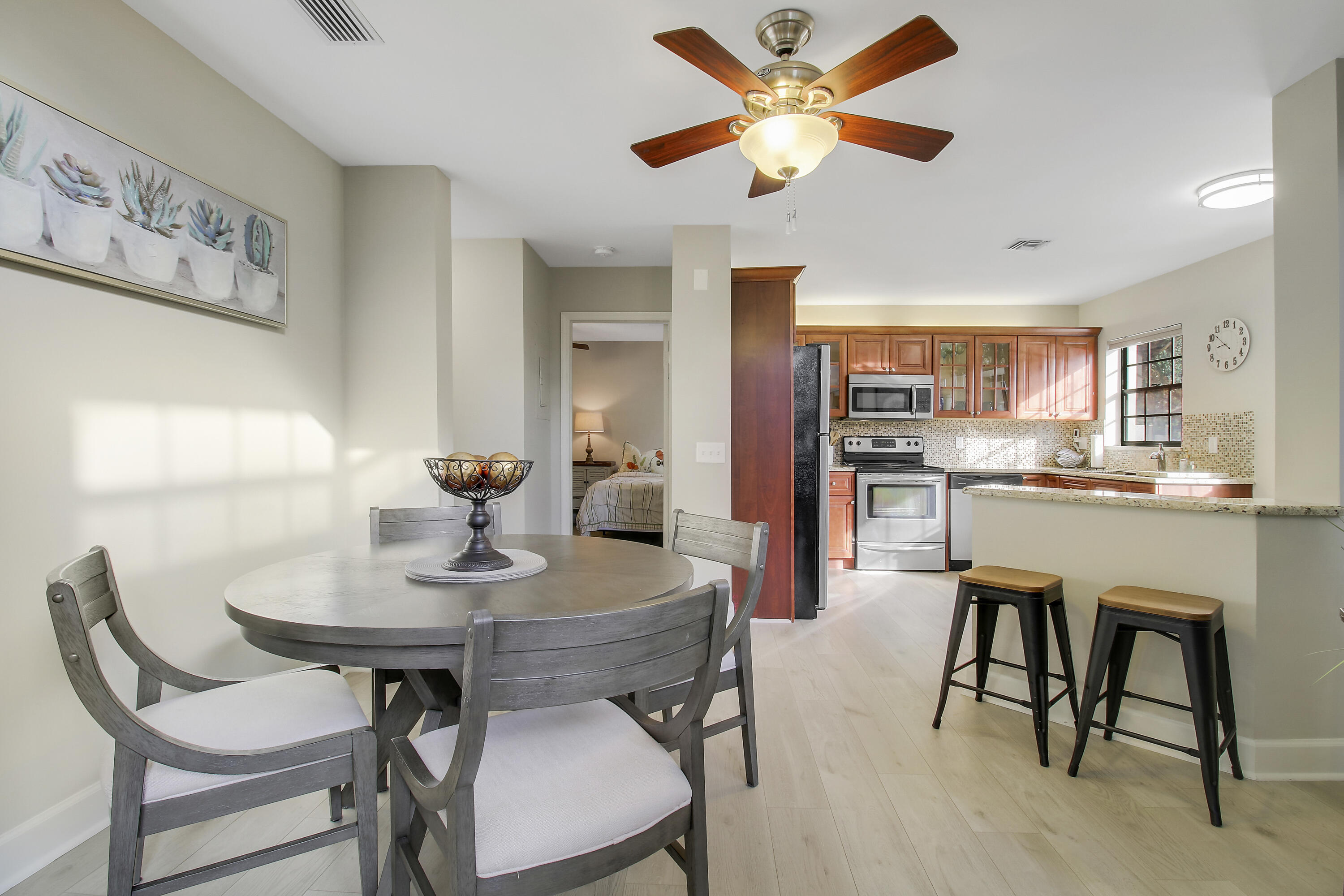 Dining area and kitchen with a round table, wood cabinets, stainless appliances, and breakfast bar.