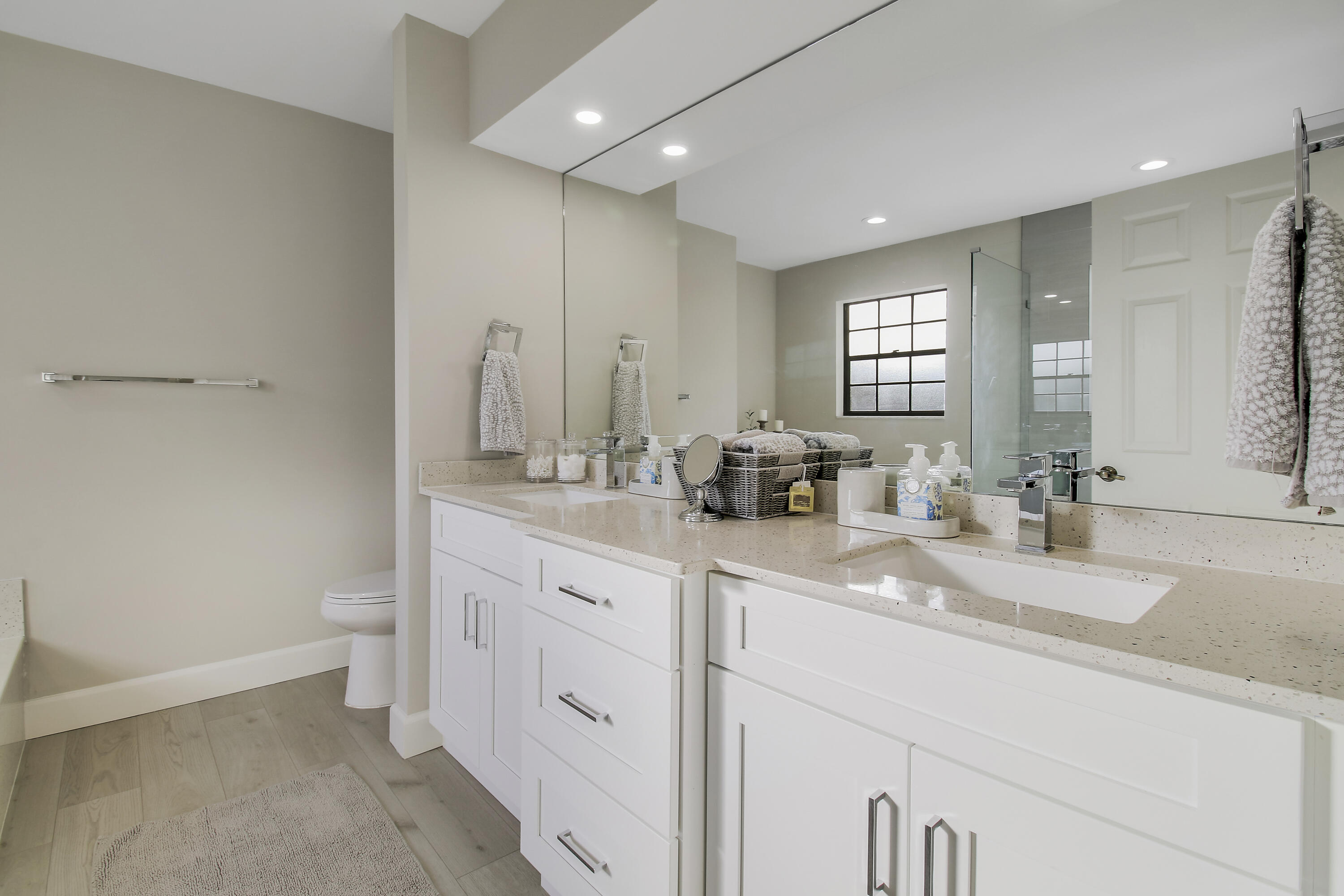 Modern bathroom with a double-sink vanity, mirrored wall, and glass shower.