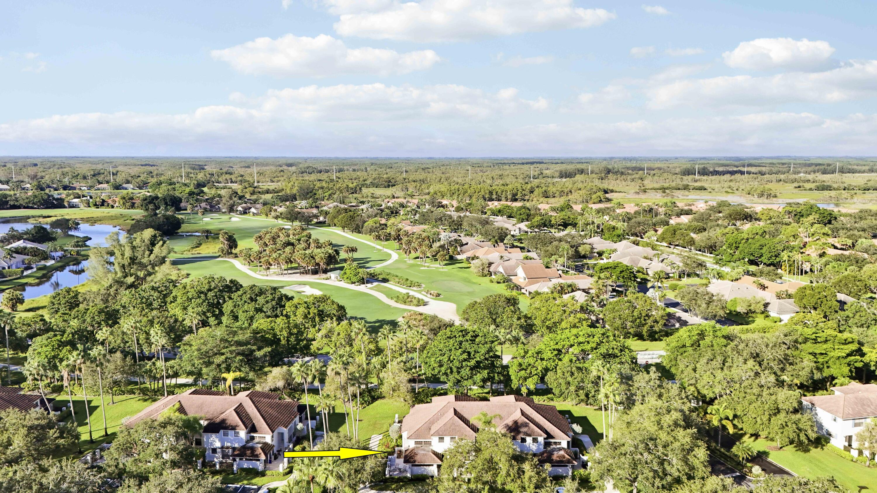 Aerial view of the home marked by an arrow beside a golf course and ponds.