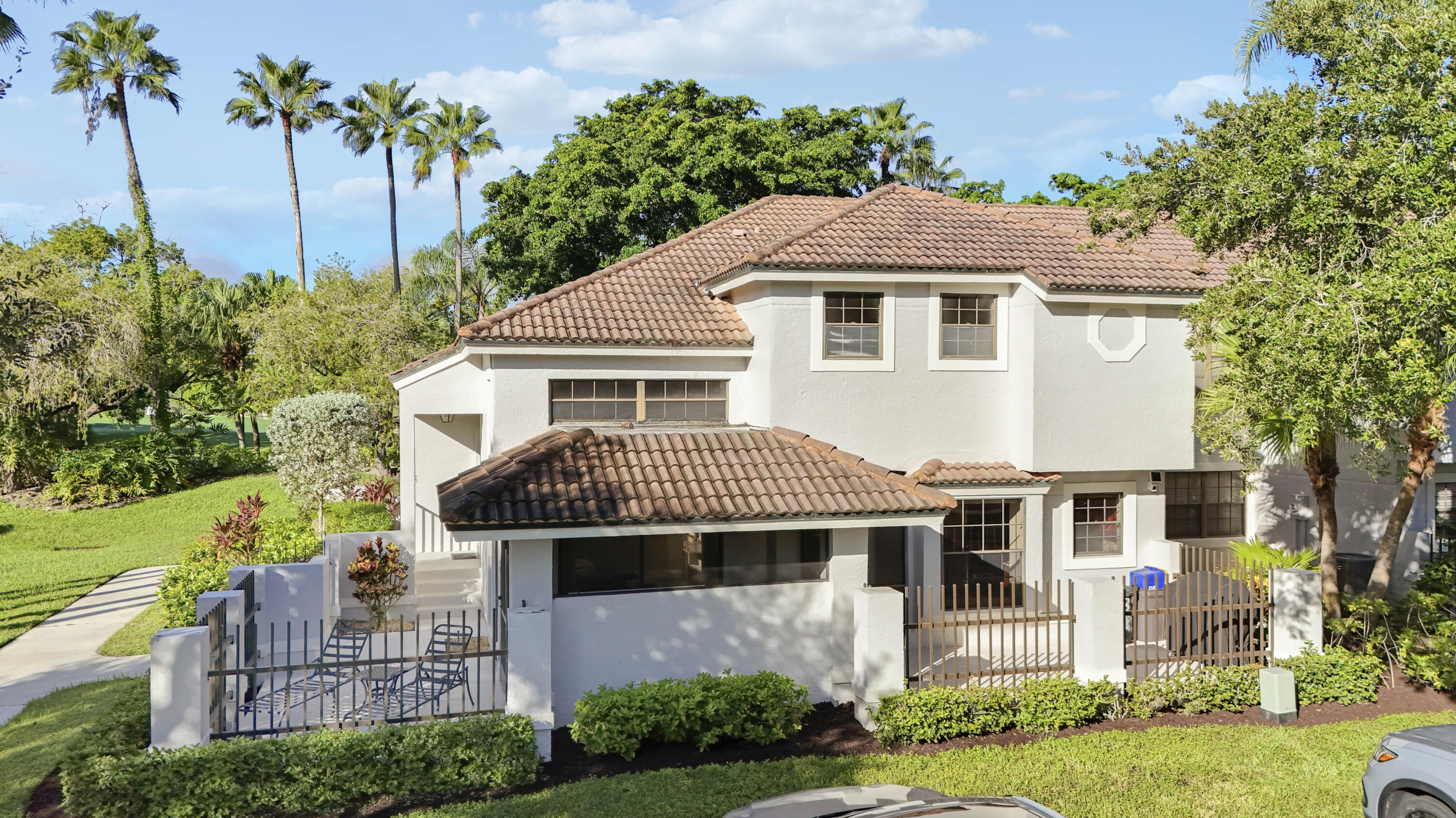 Two-story stucco home with a terracotta tile roof, screened patio, and fenced courtyard.