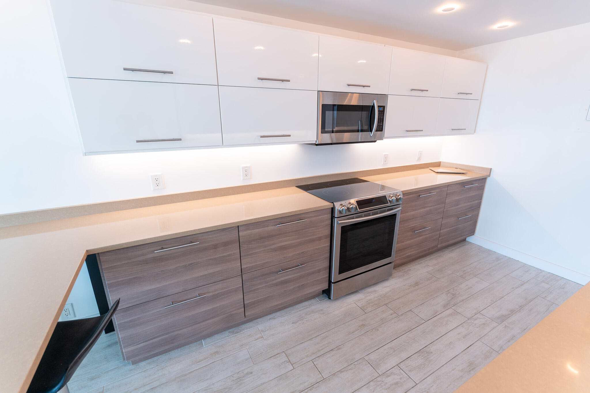 Modern kitchen with white cabinets, gray lower cabinets, and stainless steel appliances.