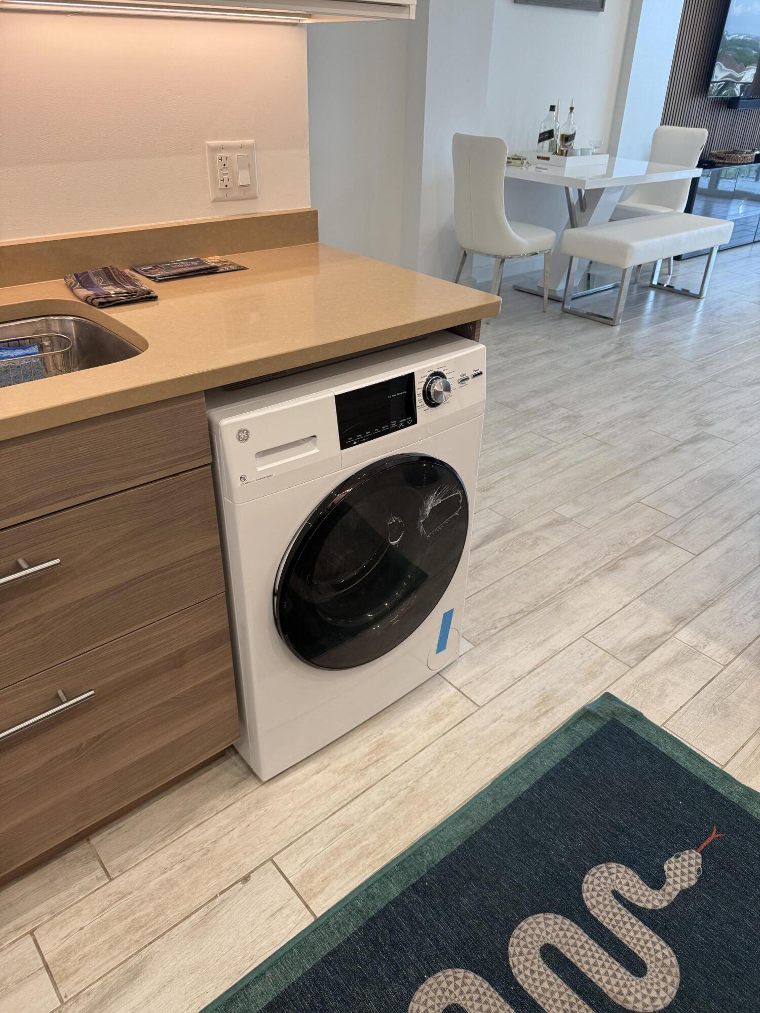 Condo kitchen with an under-counter washer-dryer, tan countertop, and white dining set.