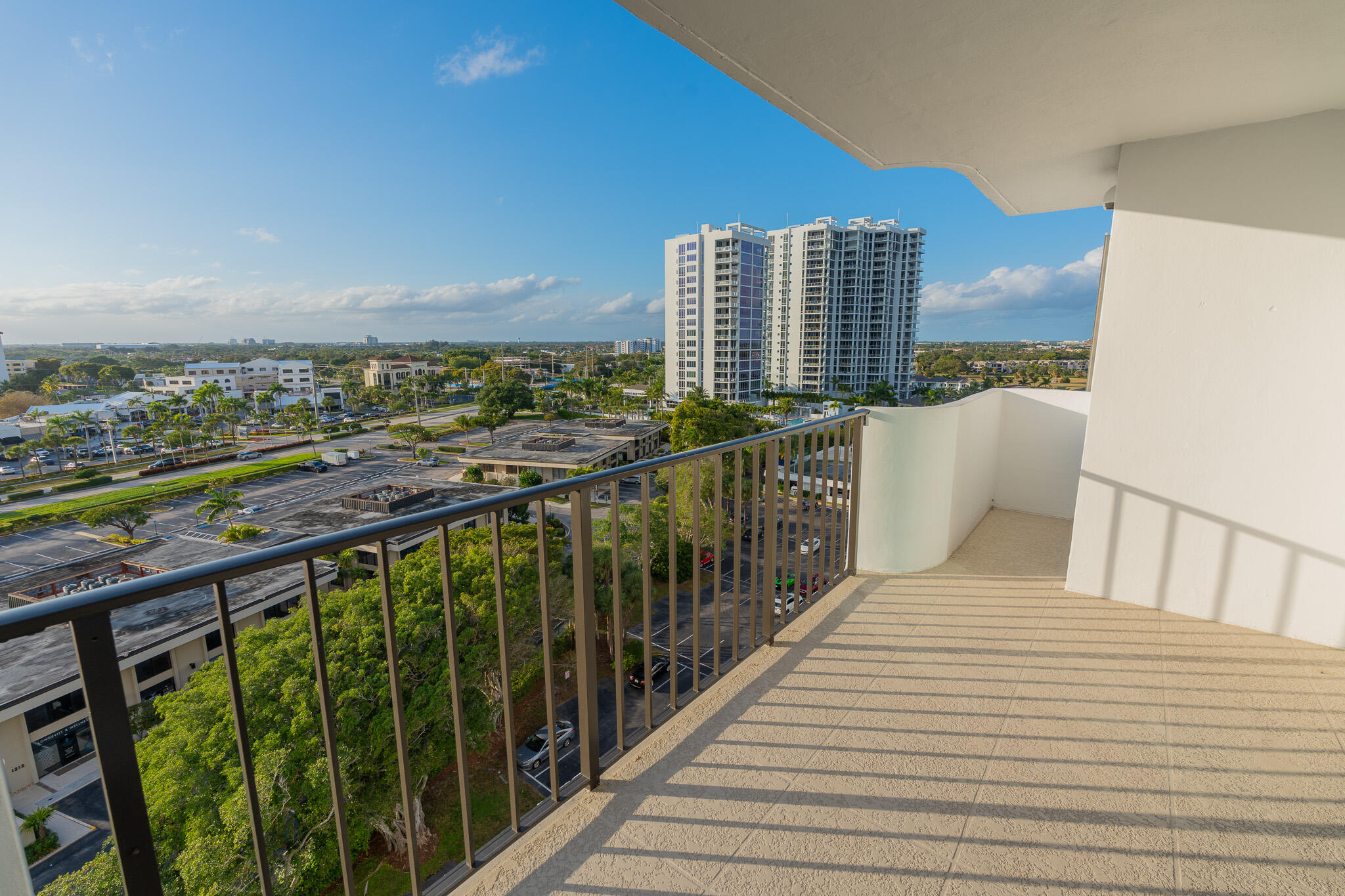 Condo balcony overlooking nearby high-rises, parking lots, and greenery.