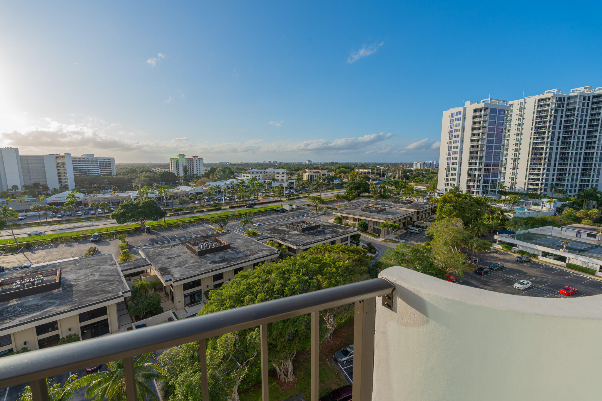 Balcony view over nearby high-rises, roads, parking lots, and greenery.
