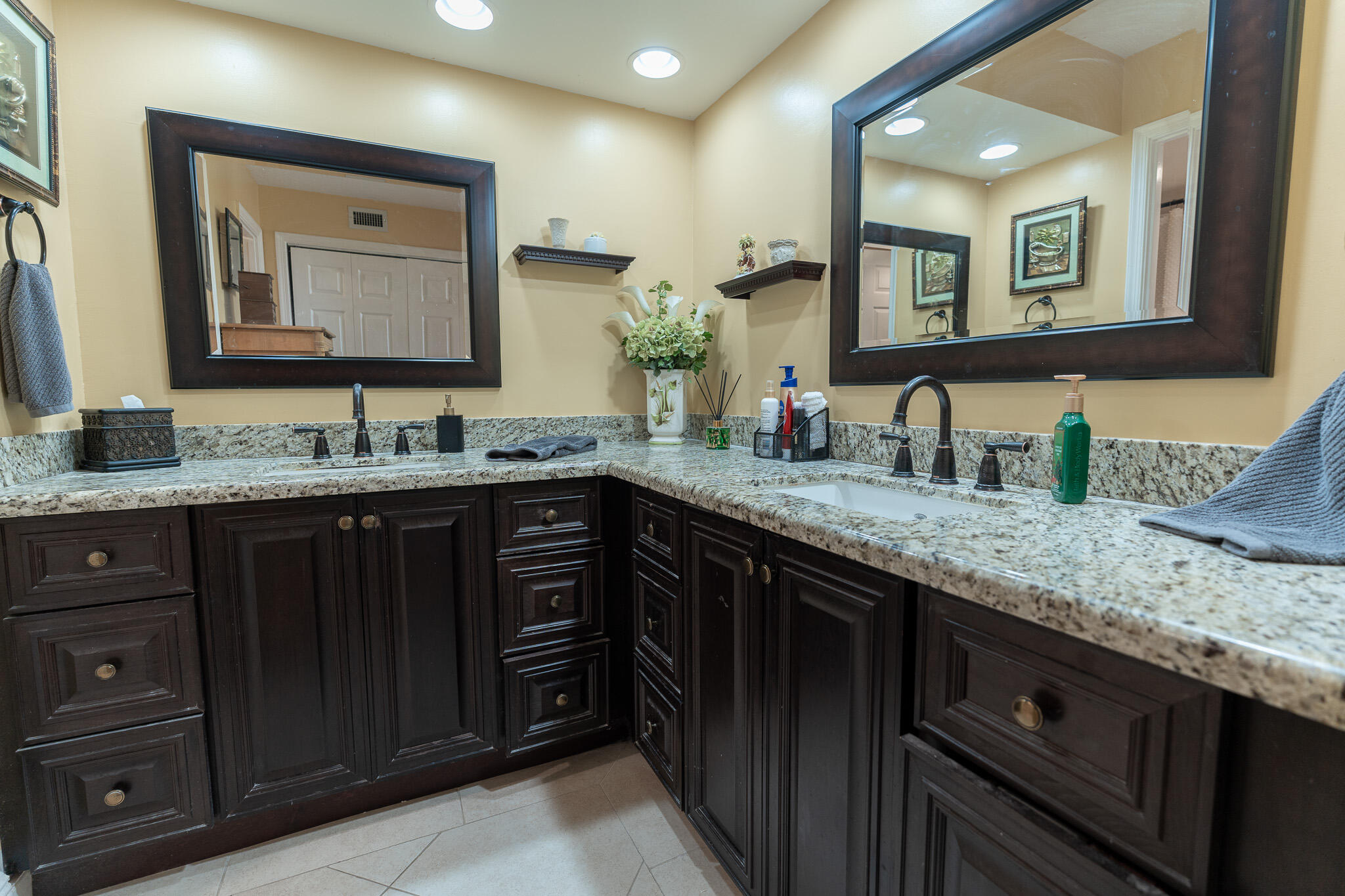 Bathroom vanity with dark wood cabinetry, granite counters, and two large framed mirrors.
