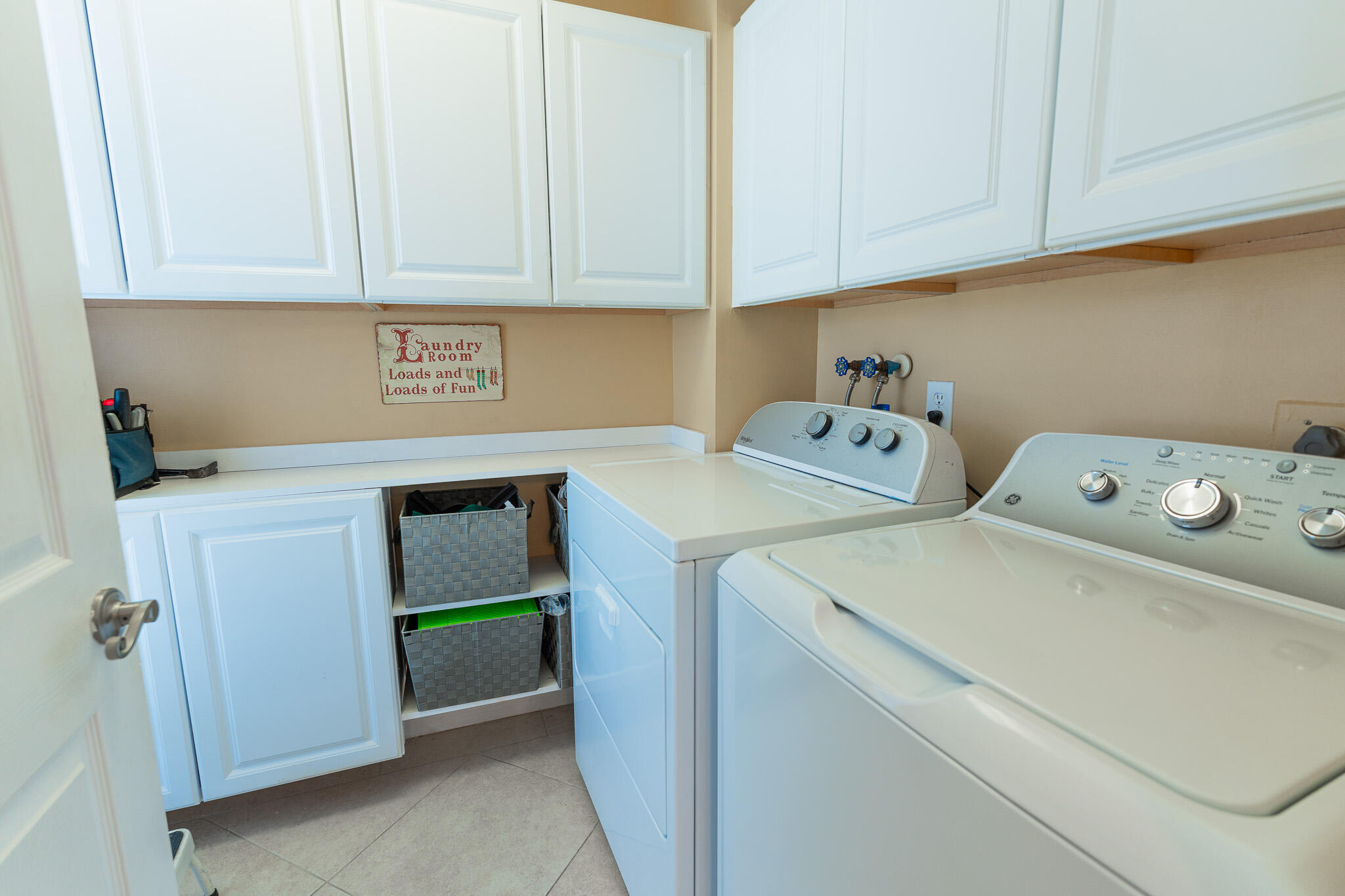 Laundry room with white cabinets, countertop storage baskets, and a washer and dryer.