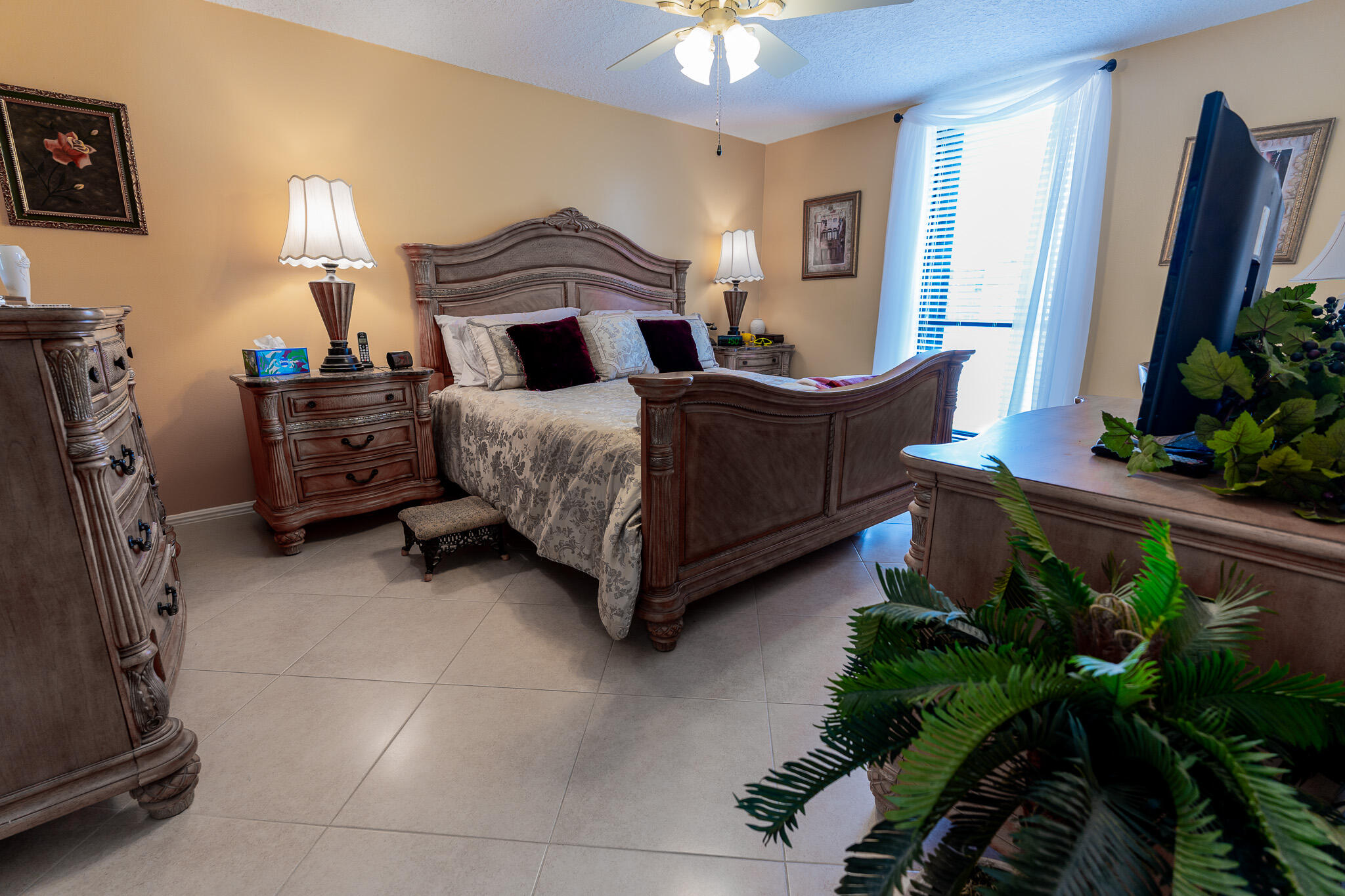 Furnished bedroom with an ornate wooden bed, matching dressers, and a bright window.