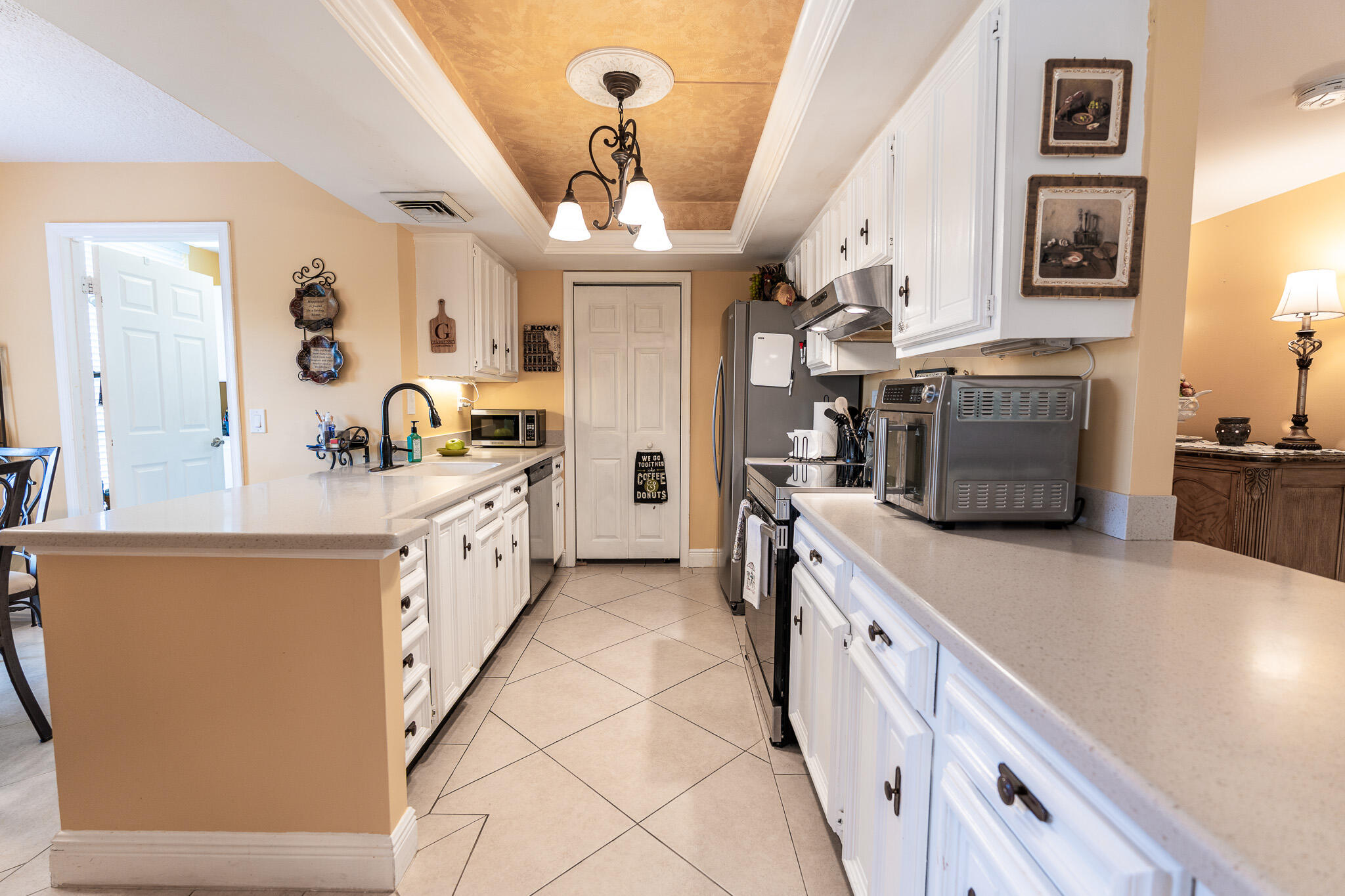 Kitchen with white cabinets, stainless steel appliances, and long counters on both sides.