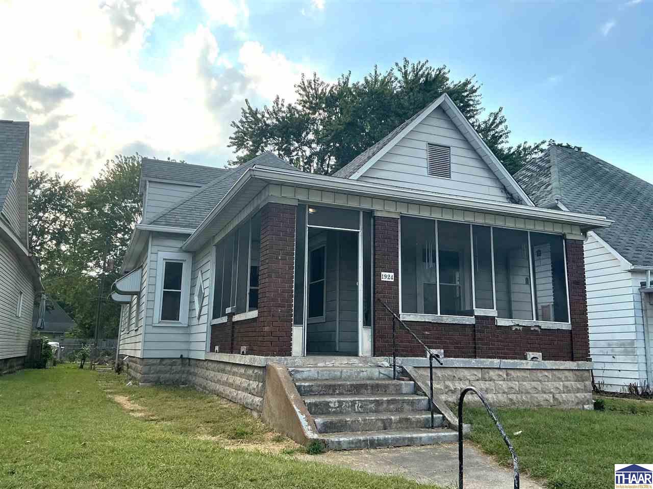 White-sided house with a brick enclosed porch and concrete front steps.