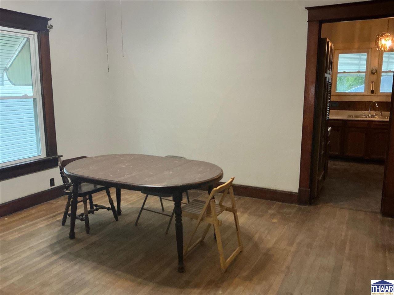 Dining room with a round table, hardwood floors, and a doorway to the kitchen.