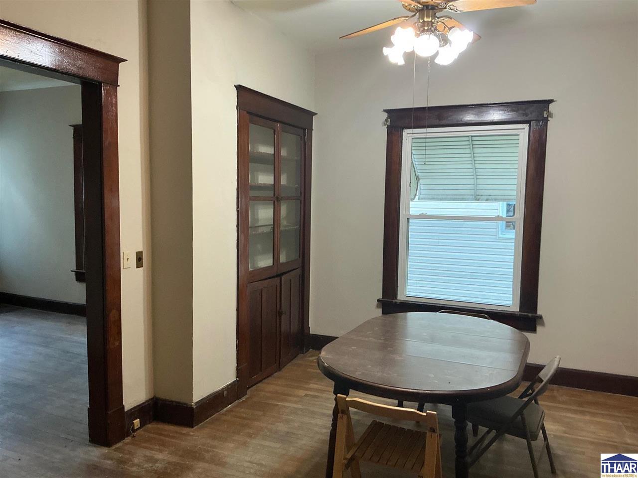 Dining room with dark wood trim, a built-in cabinet, and a table beneath a ceiling fan.