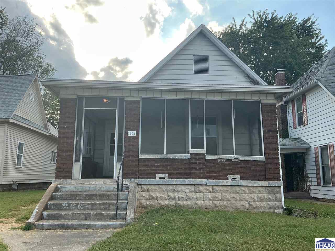 Brick house with a large screened porch, steep front gable, and broad stone steps.