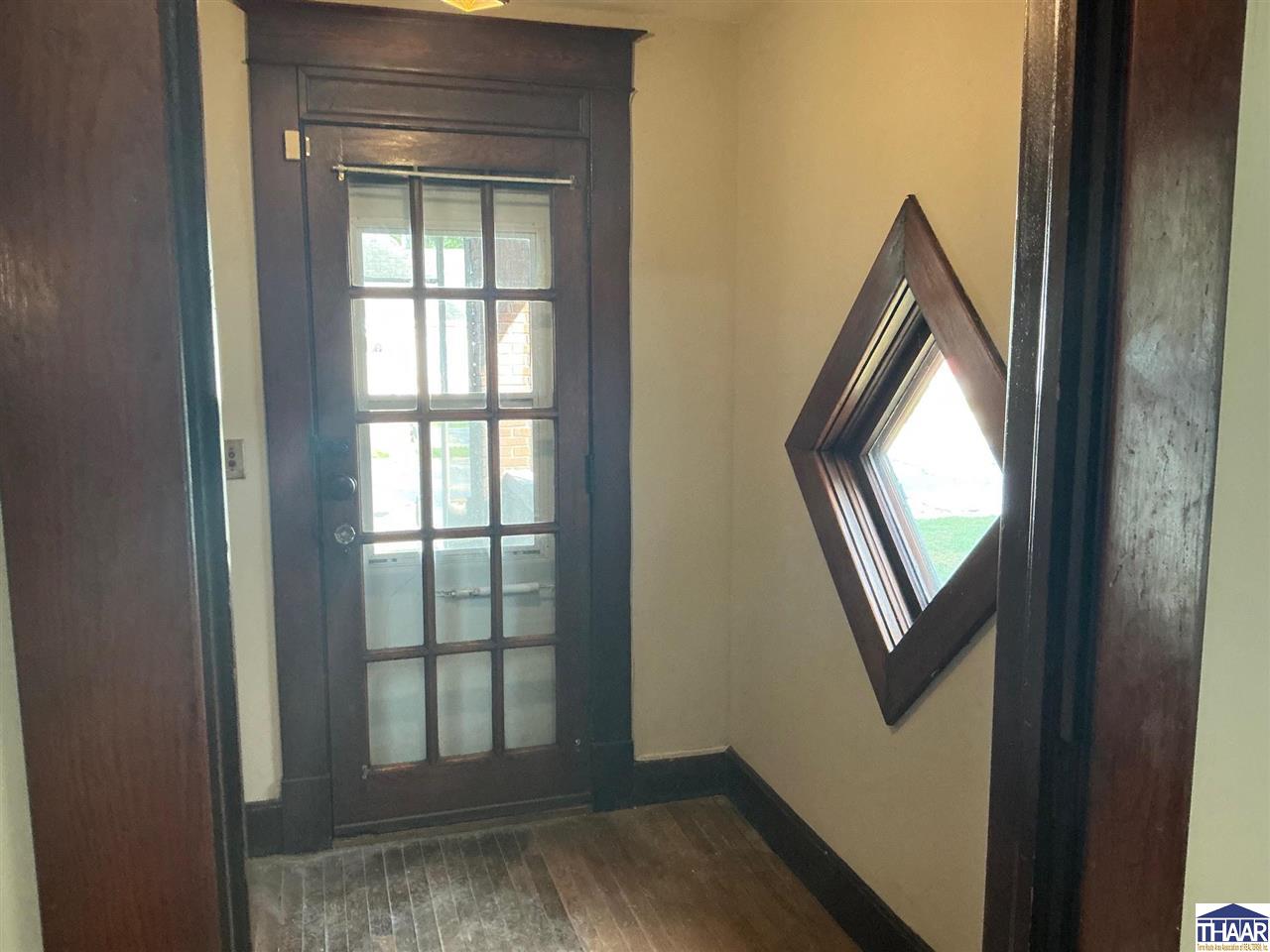 Entryway with a dark wood-framed glass door and distinctive diamond-shaped window.