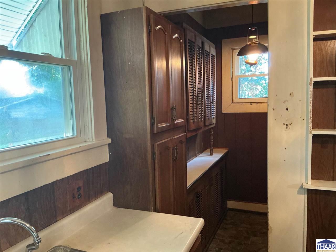 Narrow kitchen with dark wood cabinetry, a sink counter, and windows at both ends.