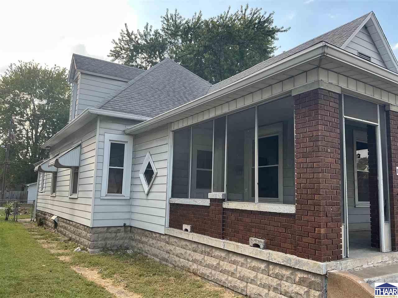 House exterior with a screened porch, red brick columns, and a stone foundation.