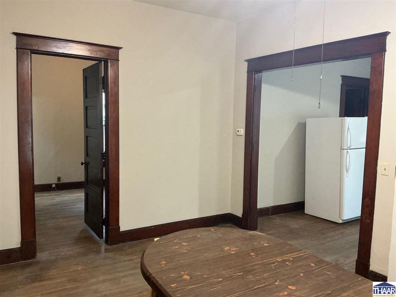 Dining area with dark wood trim, a round table, and a refrigerator through the adjoining doorway.